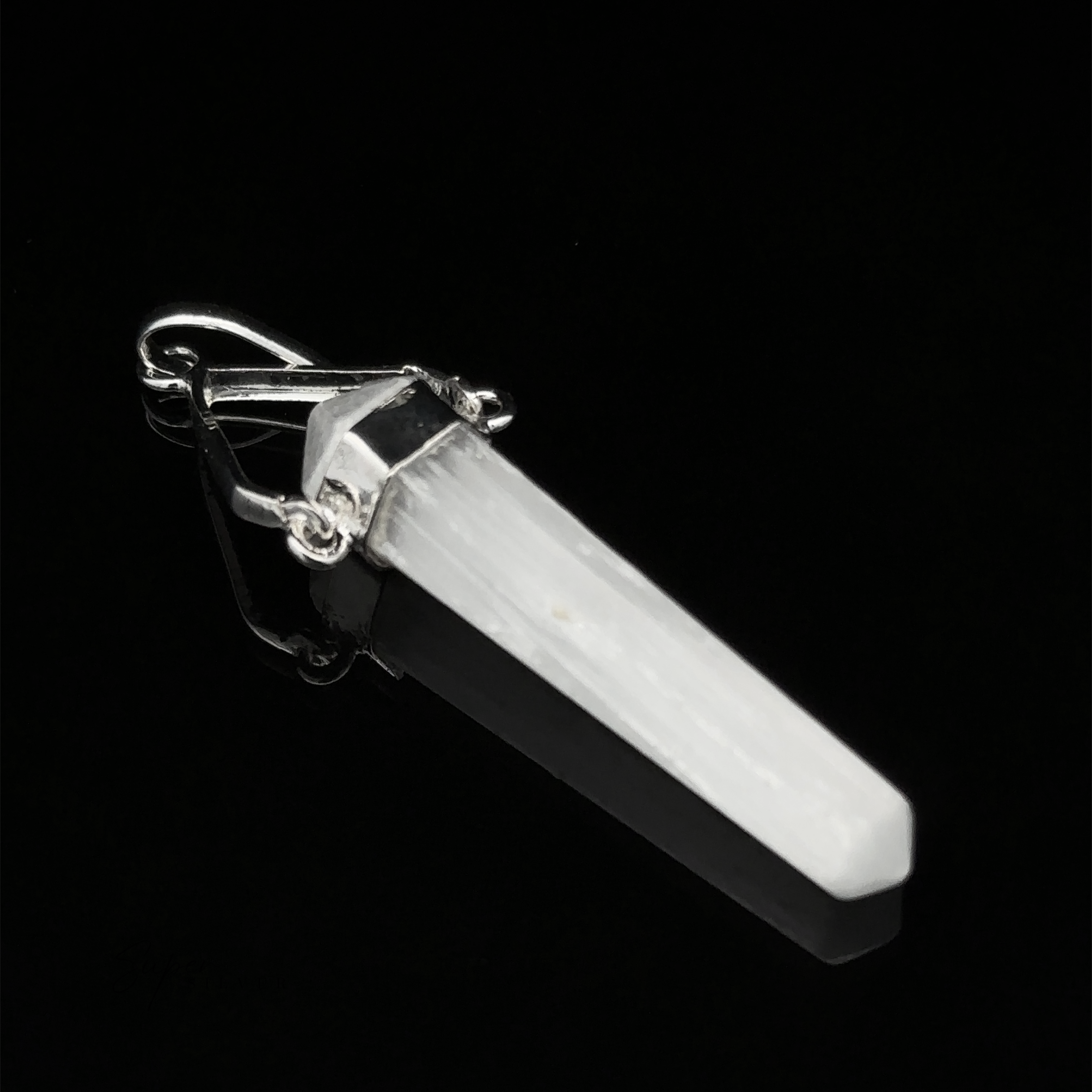 A Raw Stone Swivel Pendant, set in a silver-plated setting, on a black background.