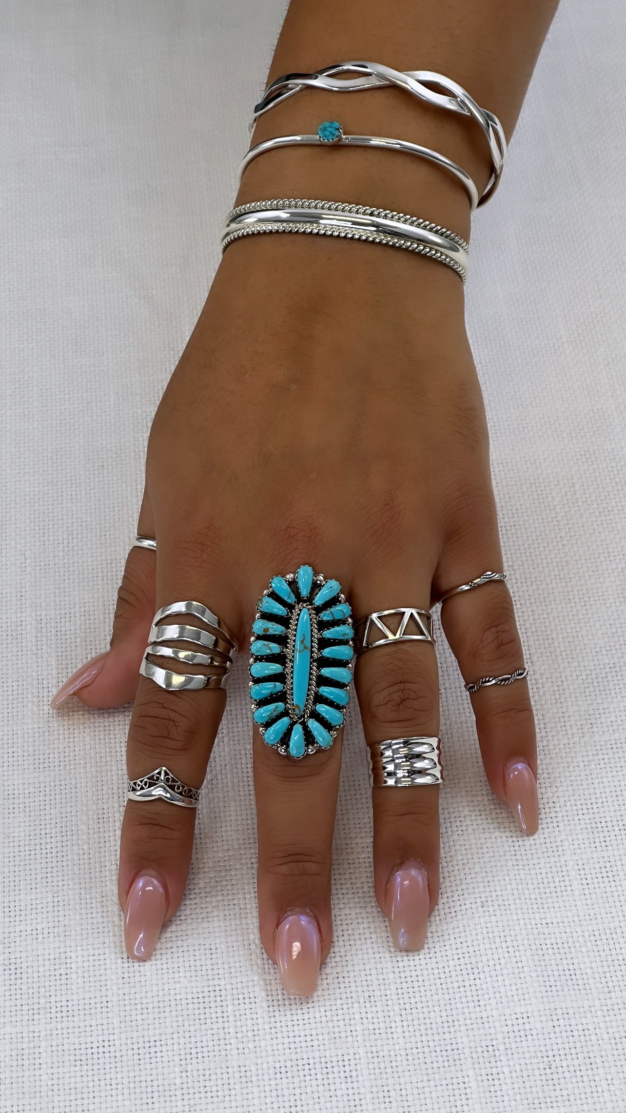 A woman's hand with the Open Shield Band, featuring turquoise and silver set on a wide tapered band made of .925 sterling silver.