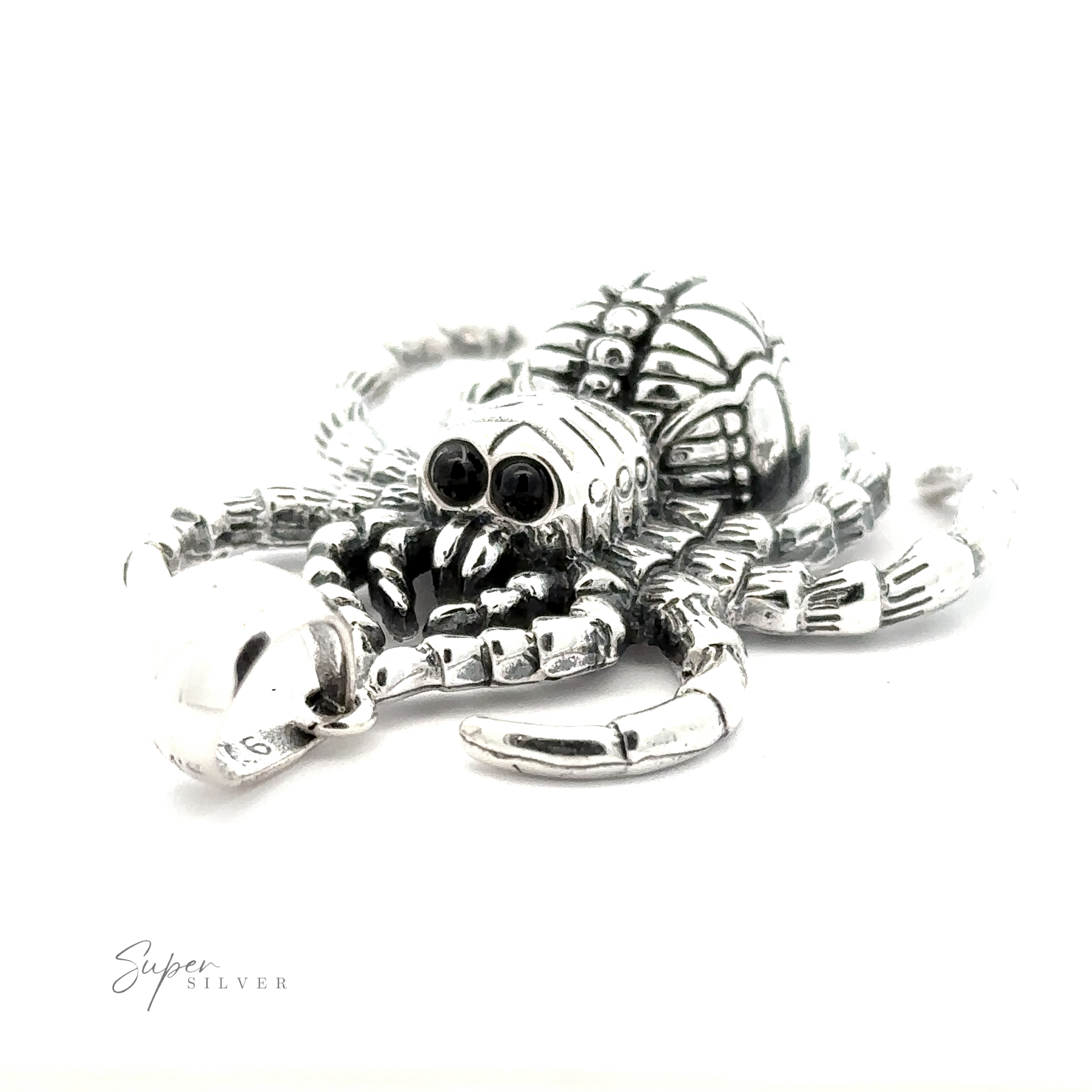 A close-up of a silver spider-shaped pendant with intricate details and black gemstone eyes. The Large Spider Pendant is on a white background, showcasing the artisanal craftsmanship of handcrafted jewelry. The text "Super Silver" is visible in the lower left corner.