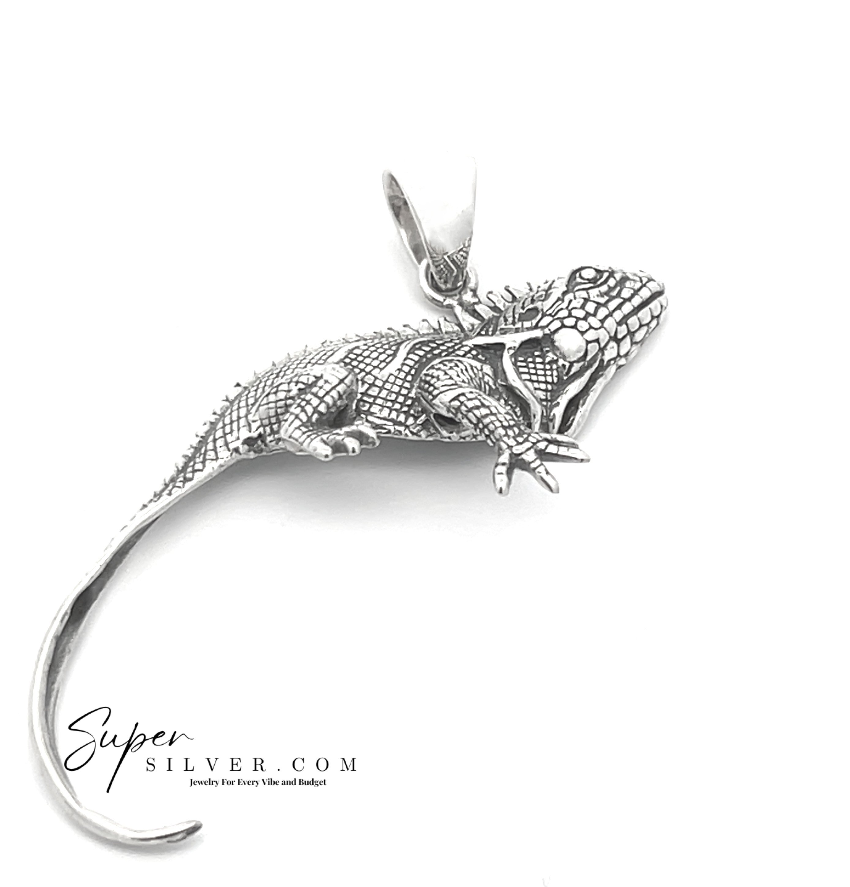 The Iguana Pendant features intricate scales and limbs in sterling silver, shown on a white background with the Super Silver logo. It belongs to the unique Artssina Collection, perfect for iguana jewelry lovers.