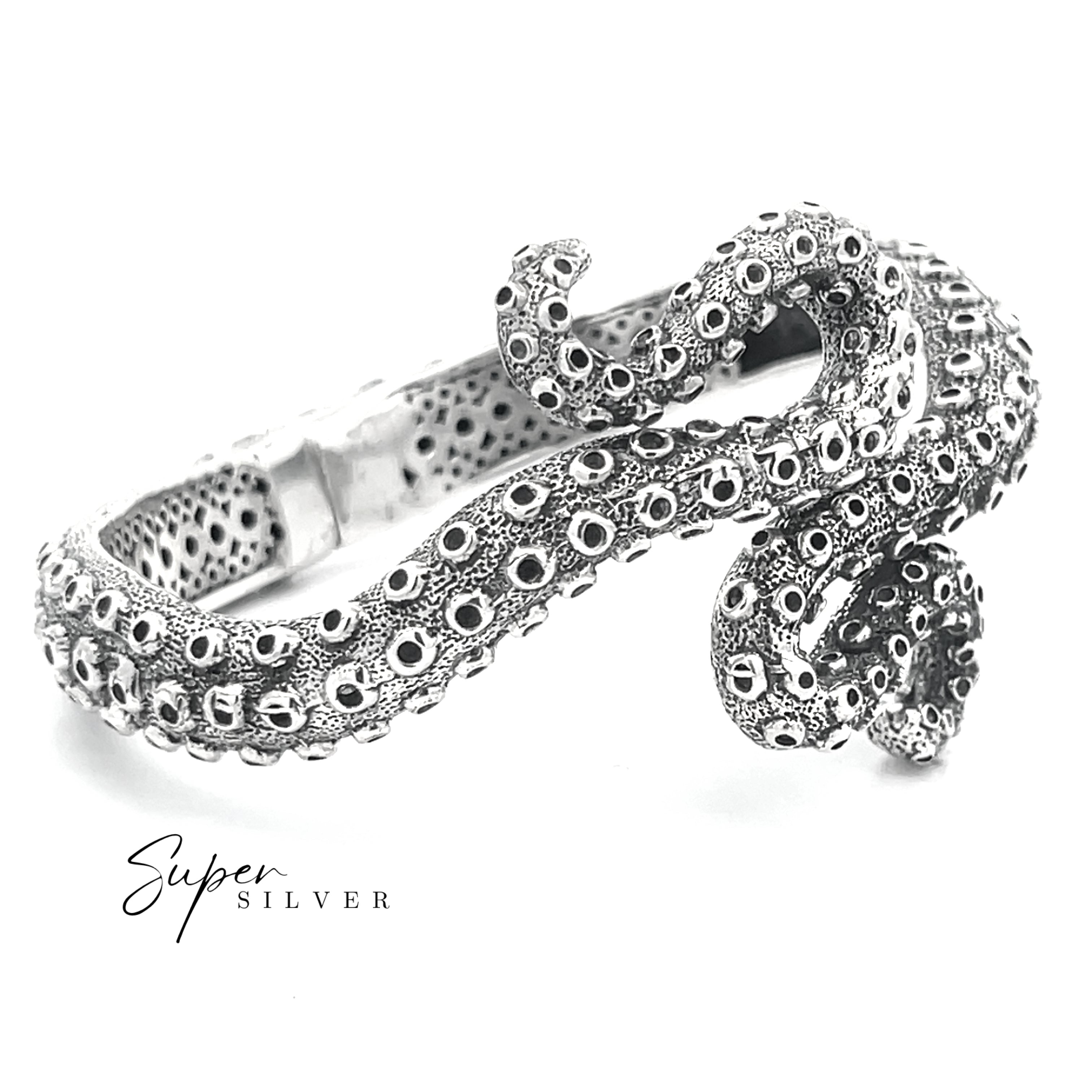 The Tentacle Hinge Cuff is a sterling silver bracelet with textured circular patterns, shaped like an octopus tentacle, shown on a white background. “Super Silver” is displayed in the corner.