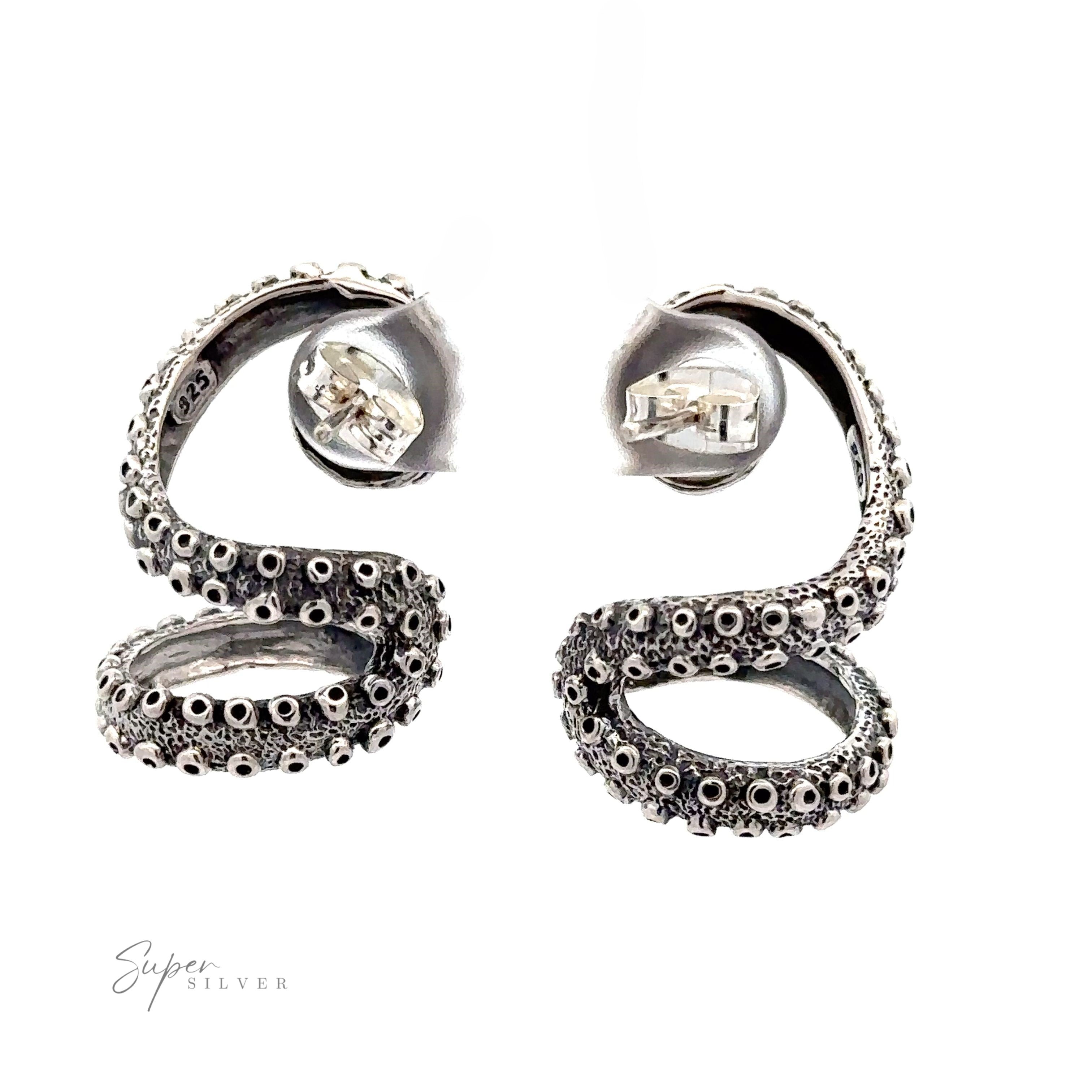 A pair of coiled silver earrings adorned with circular patterns and small clear stones, resembling tentacles. The "Super Silver" logo is visible in the bottom left corner. These handcrafted sterling silver pieces capture the essence of Curled Tentacle Earrings.