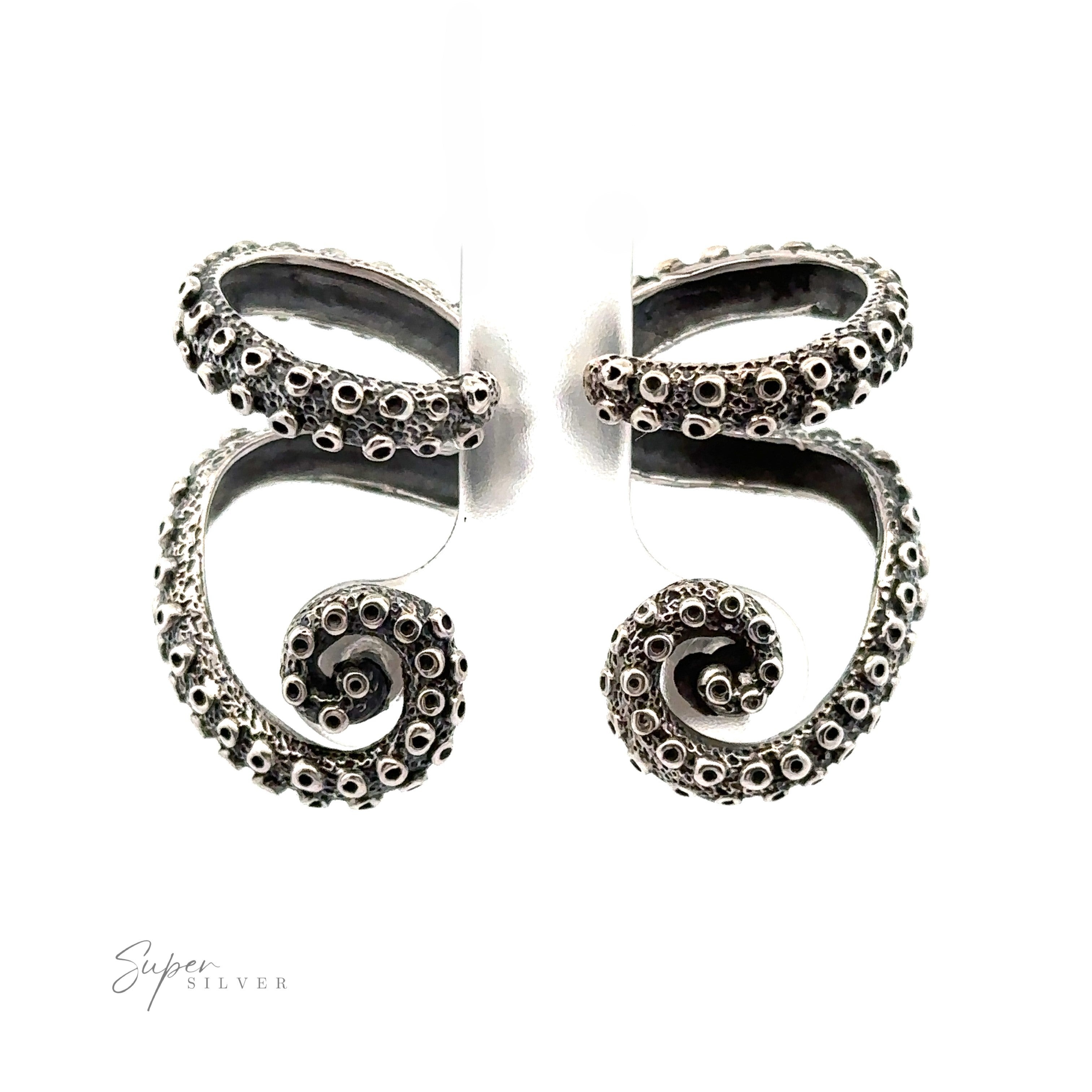 A pair of handcrafted sterling silver earrings designed to resemble octopus tentacles, intricately detailed with suction cups, and displayed against a white background. These Curled Tentacle Earrings embody the essence of ocean allure jewelry.