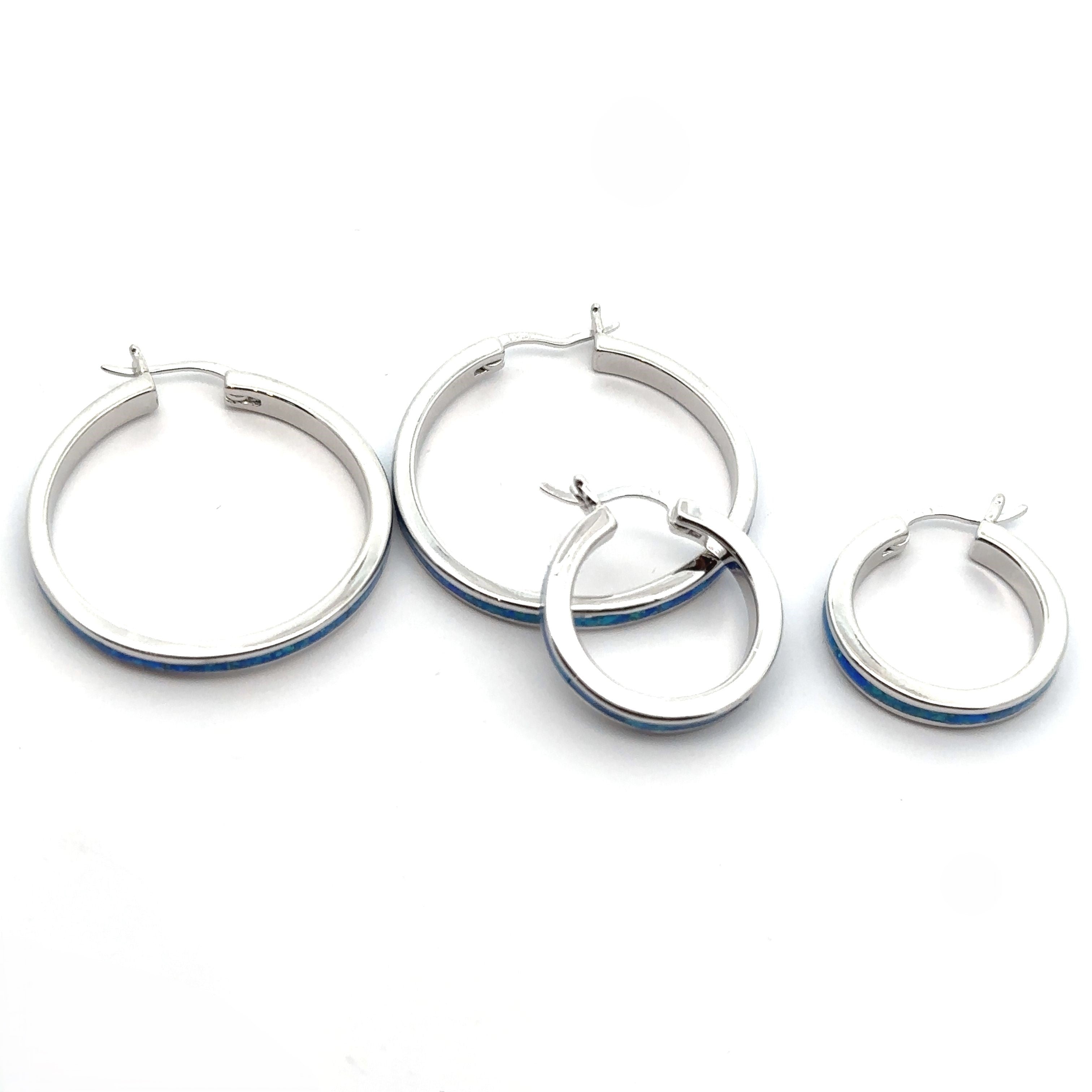 Blue Lab-Created Opal hoop earrings, available in two distinct sizes, stylishly displayed on a white background. The sparkling rhodium finish adds to their allure and sophistication.