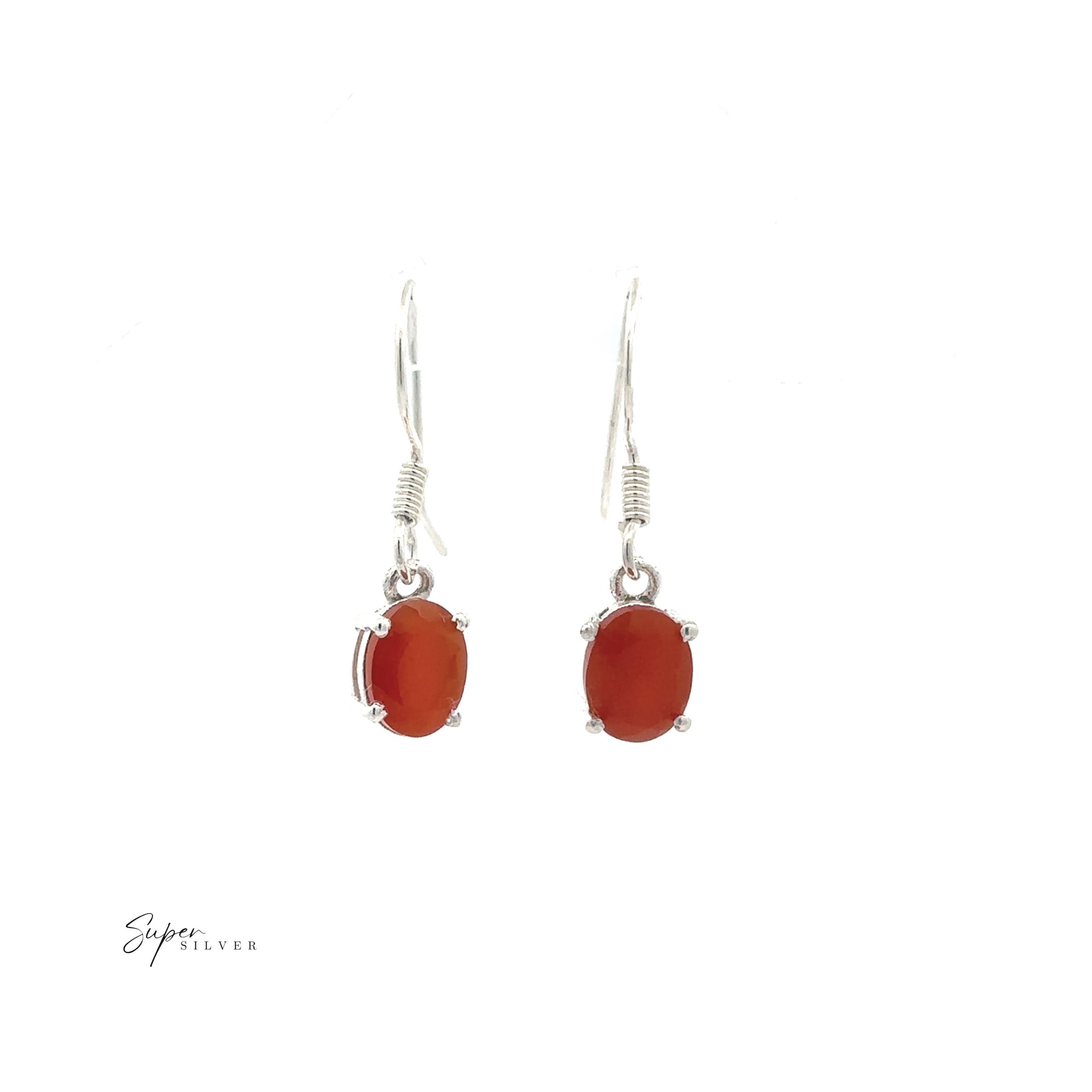The Brilliant Oval Gemstone Earrings are sterling silver with prong-set, oval red gemstones, shown on a white background.