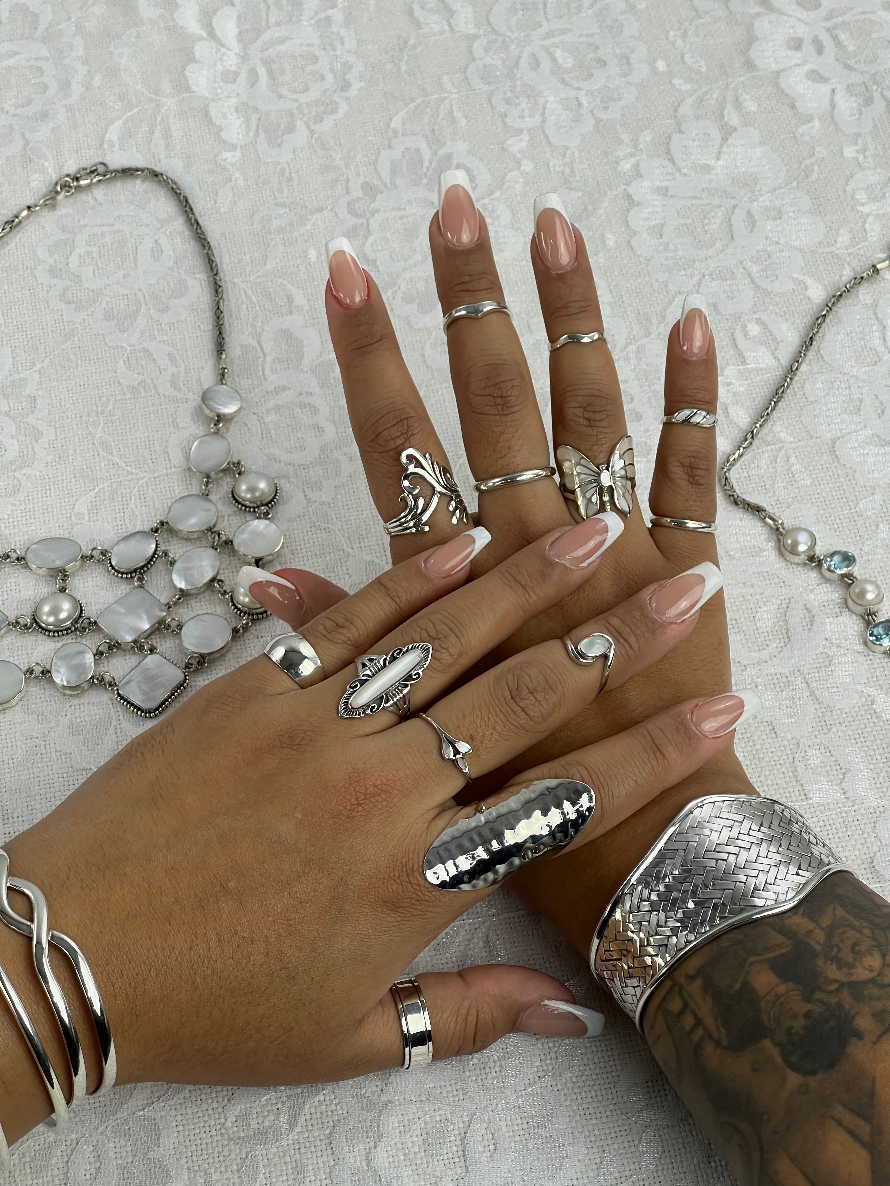 A woman's hands adorned with a wide diamond shaped basket weave cuff bracelet, showcasing .925 Sterling Silver jewelry.