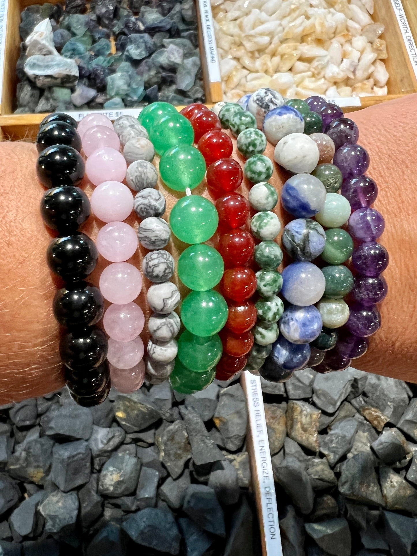 
                  
                    A woman's hand is holding a variety of Super Silver Beaded Stone Bracelets, including stretch bracelets and gemstone bracelets.
                  
                