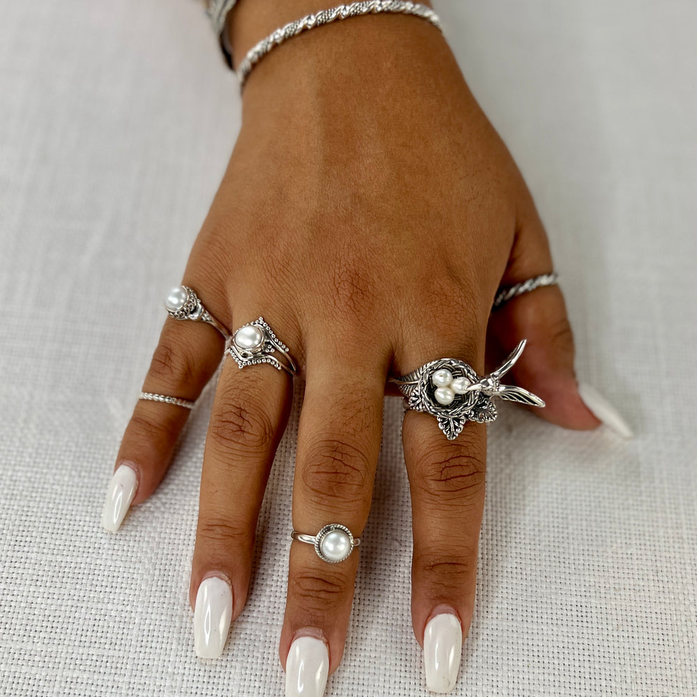 A woman's hand adorned with Super Silver's Hummingbird With Nest of Pearls Ring.