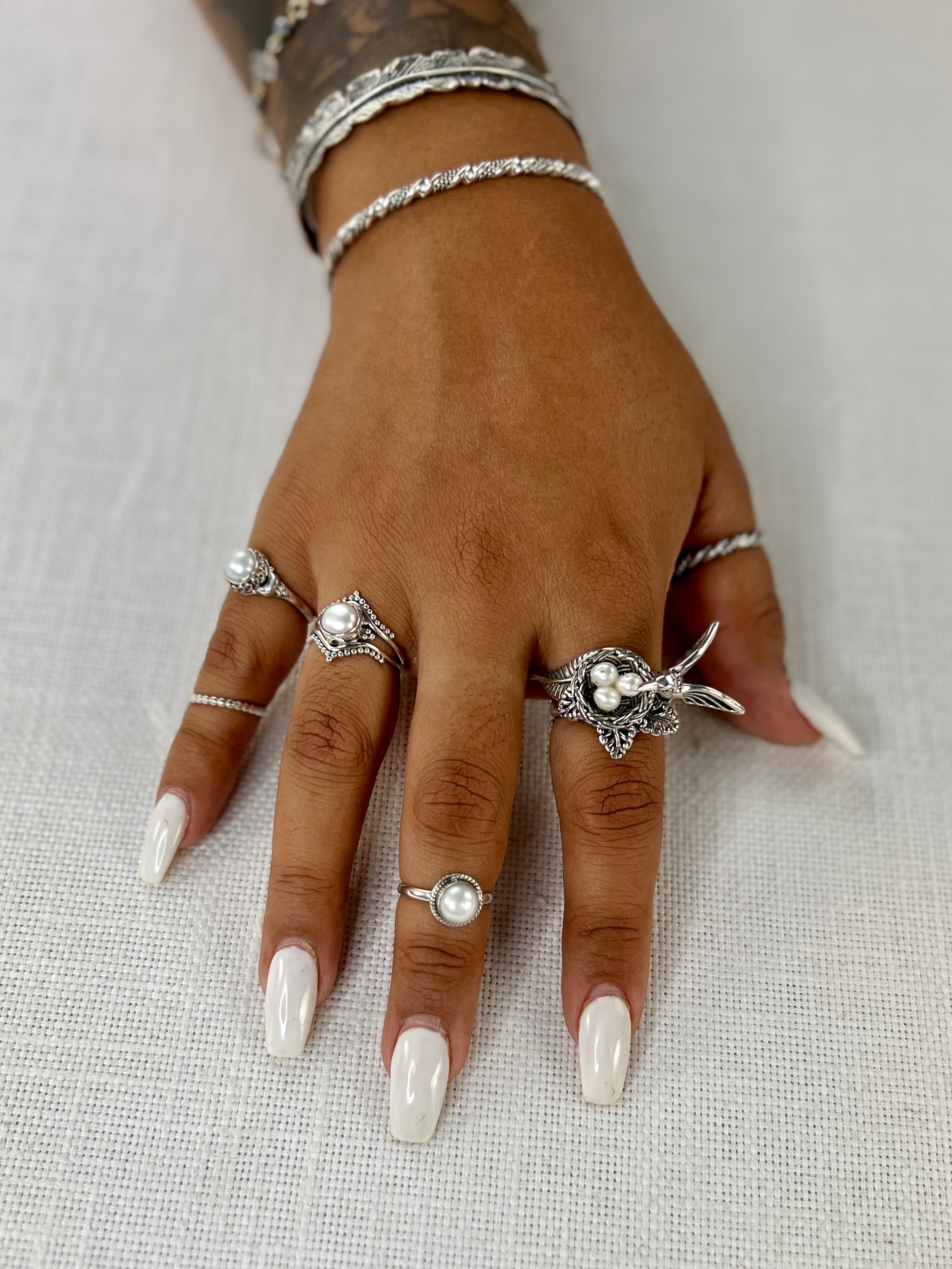A woman's hand adorned with Super Silver's Hummingbird With Nest of Pearls Ring.