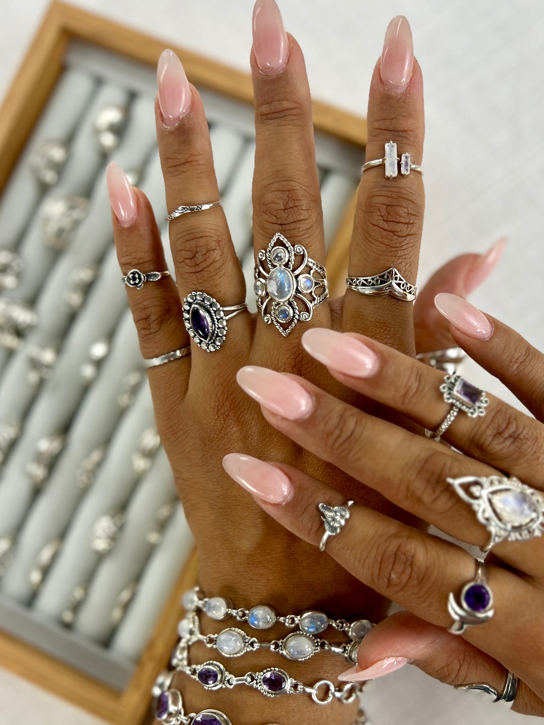 A woman's hand adorned with pink nails and a Super Silver Filigree Chevron Ring exudes a chic and unique look, while maintaining its Victorian charm.