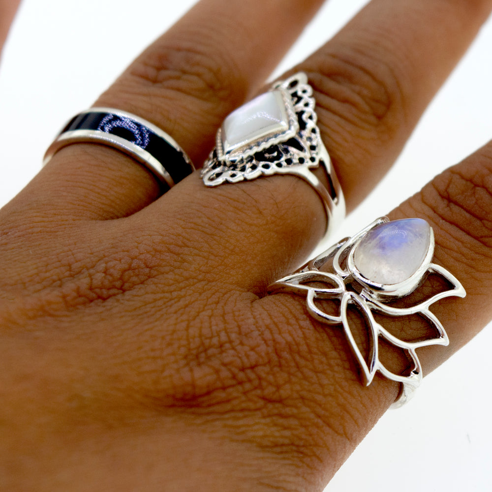 
                  
                    Close-up of a hand wearing three unique Online Exclusive Teardrop Stone Lotus Rings on different fingers, set against a plain white background.
                  
                