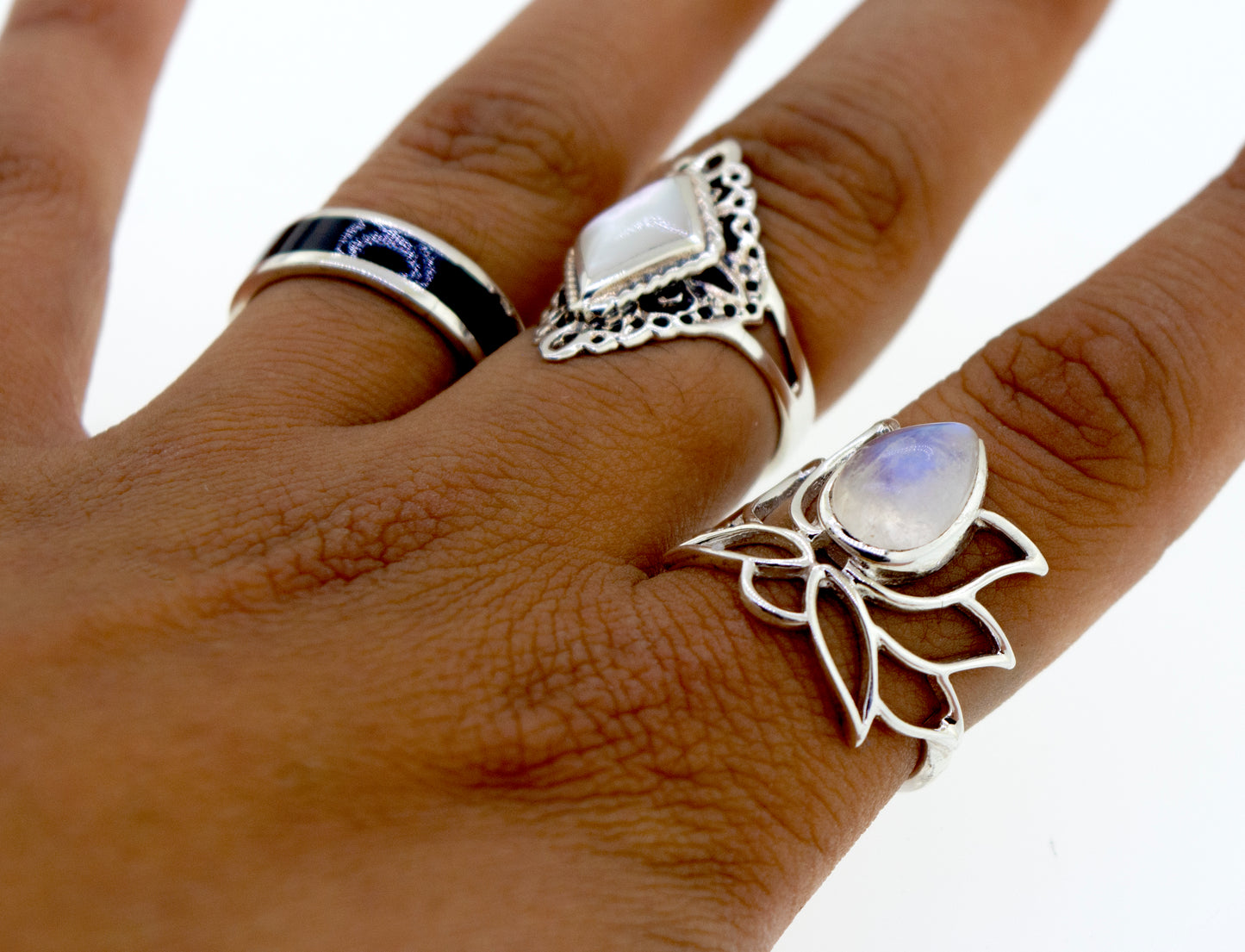 
                  
                    Close-up of a hand wearing three unique Online Exclusive Teardrop Stone Lotus Rings on different fingers, set against a plain white background.
                  
                