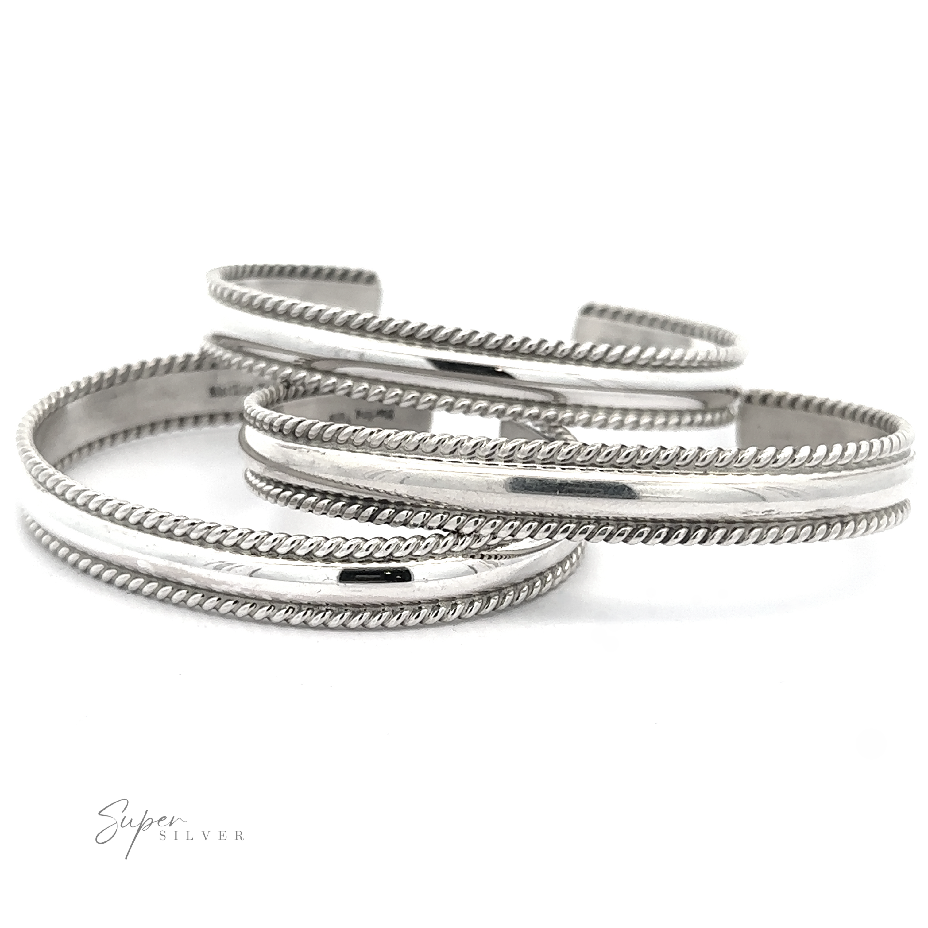 Three polished Native American Handmade Silver Rope Cuffs with rope-like edges, overlapping each other on a white background. The logo "Super Silver" is in the bottom left corner, showcasing these stunning statement pieces.