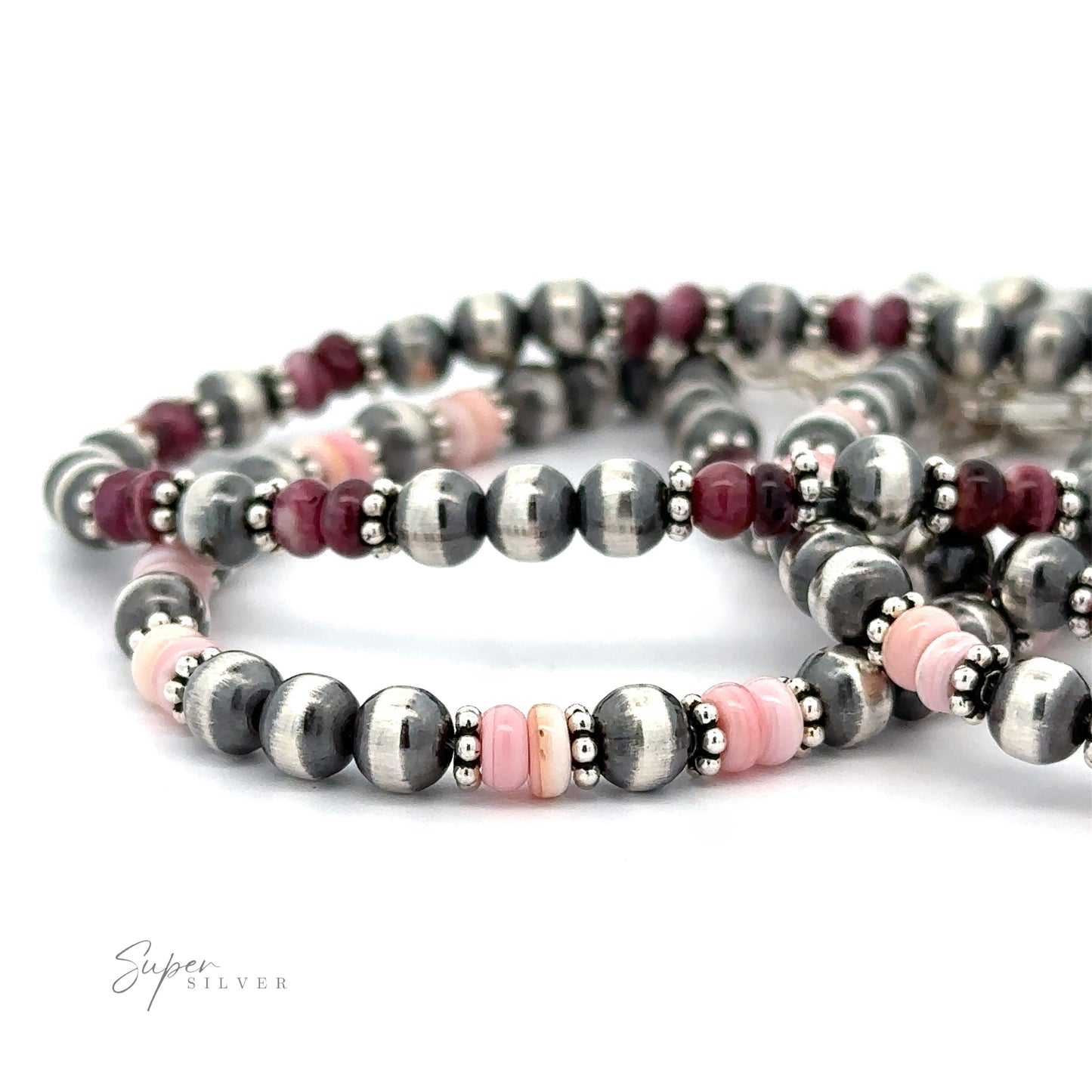 A close-up of three Native American Shell and Navajo Pearl Bracelets featuring pink and metallic gray beads with a signature in the corner.
