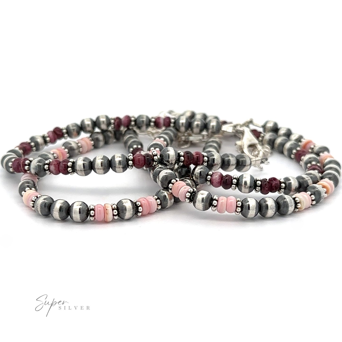 A bracelet made of silver and pink beads, featuring a toggle clasp, inspired by Native American Shell and Navajo Pearl bracelets, displayed against a white background.