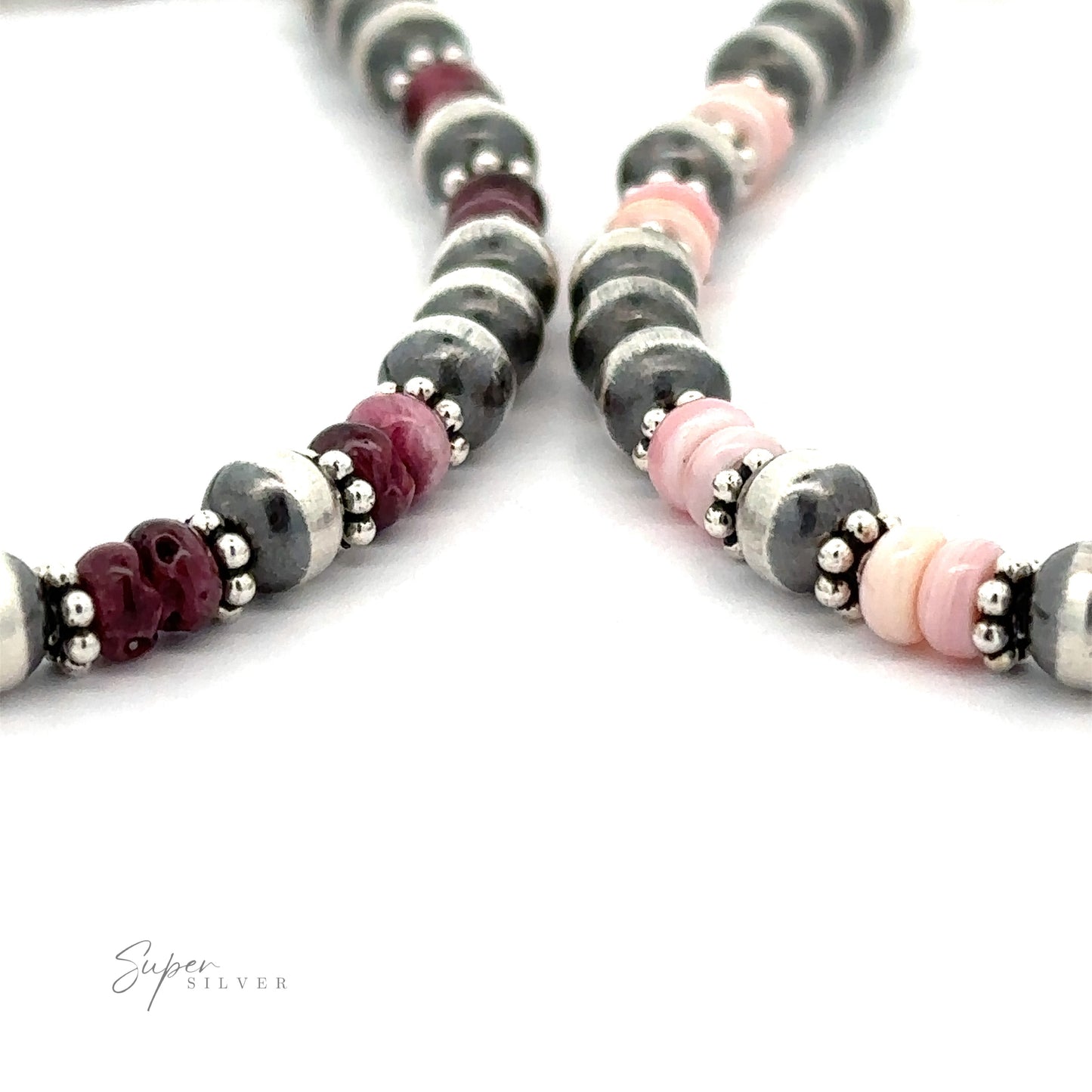 
                  
                    Close-up of a Native American Shell and Navajo Pearl Bracelet with alternating Navajo pearls, pink, and burgundy beads on a white background.
                  
                