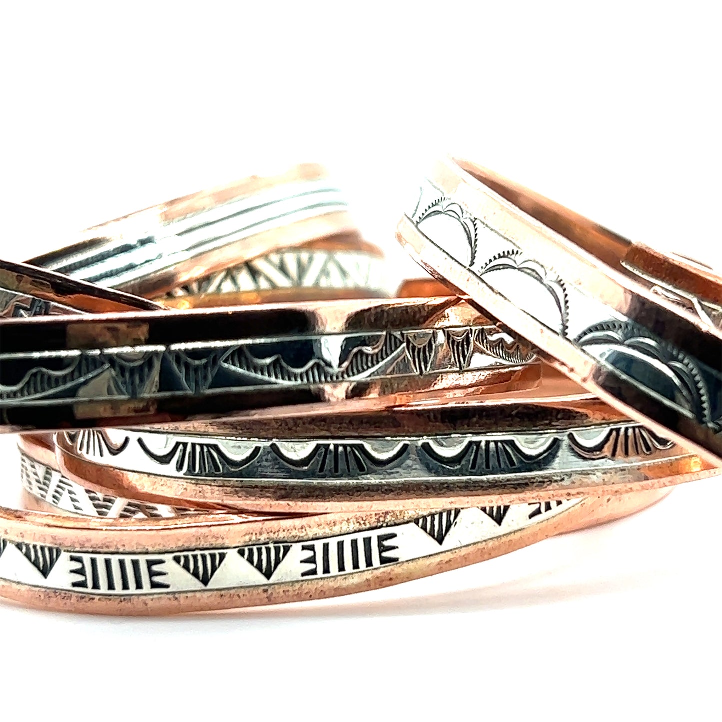
                  
                    A handcrafted stack of Super Silver copper bracelets with Native American designs.
                  
                
