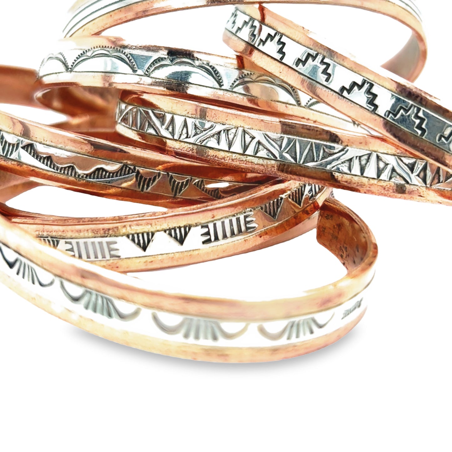 
                  
                    A stack of Super Silver Native American Handmade Copper And Silver Bracelets with designs.
                  
                