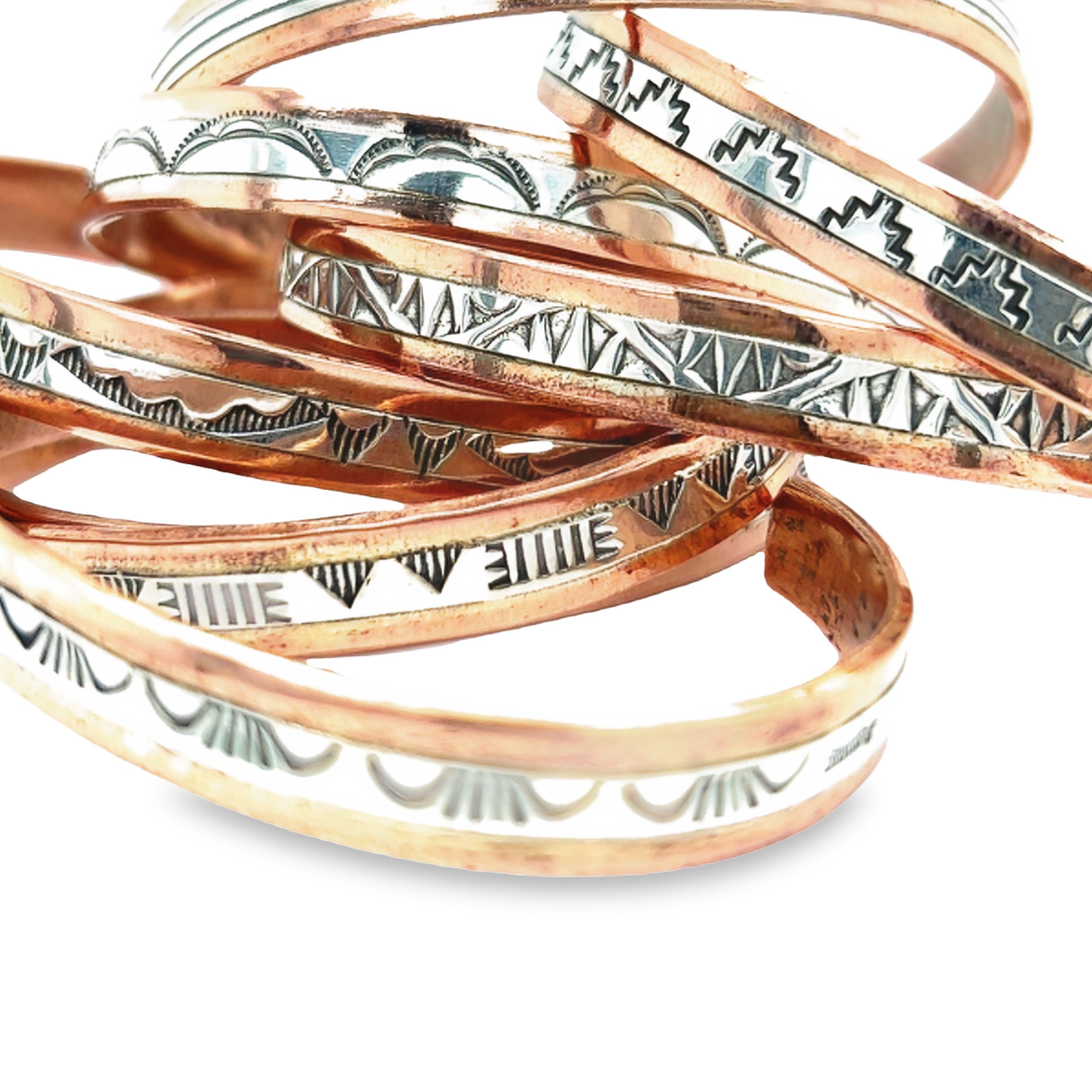 A stack of Super Silver Native American Handmade Copper And Silver Bracelets with designs.