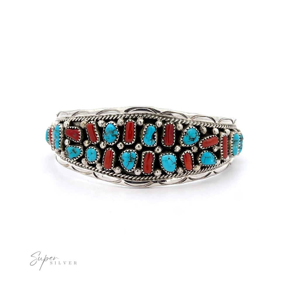 
                  
                    Native American Cluster Turquoise Cuff Bracelet with intricate detailing, inlaid with multiple turquoise and coral stones, exhibited against a white background.
                  
                
