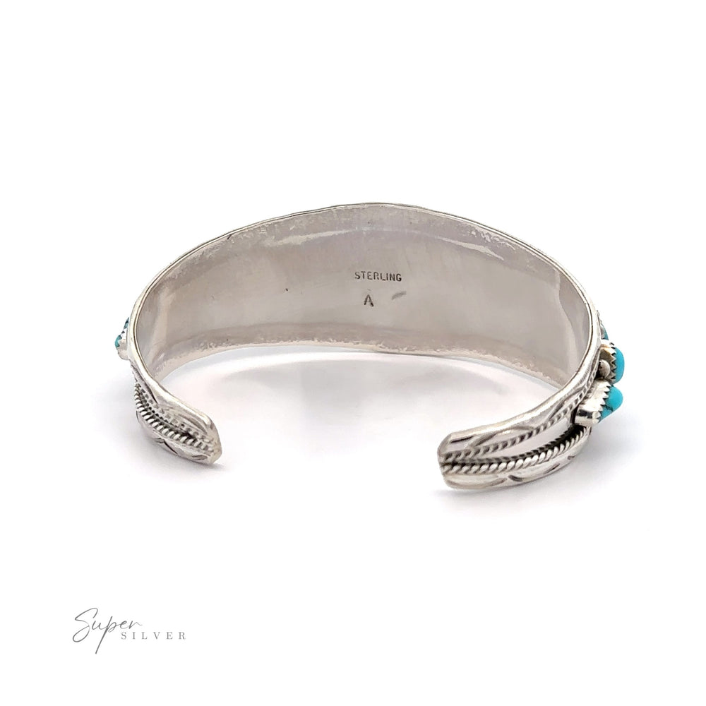 
                  
                    Native American Cluster Turquoise Cuff Bracelet with a feather design at each end and a small turquoise gemstone, reflecting Southwest charm.
                  
                