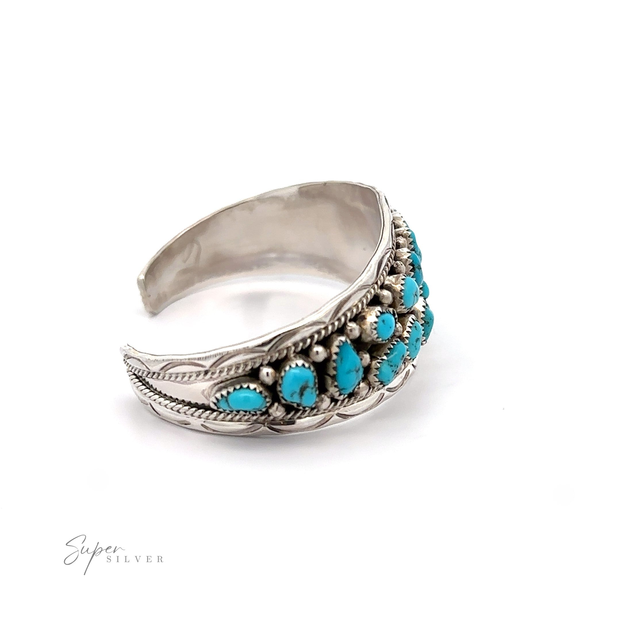 Native American Cluster Turquoise Cuff Bracelet featuring a feather design with multiple small turquoise stones, evoking Southwest charm, displayed against a white background.