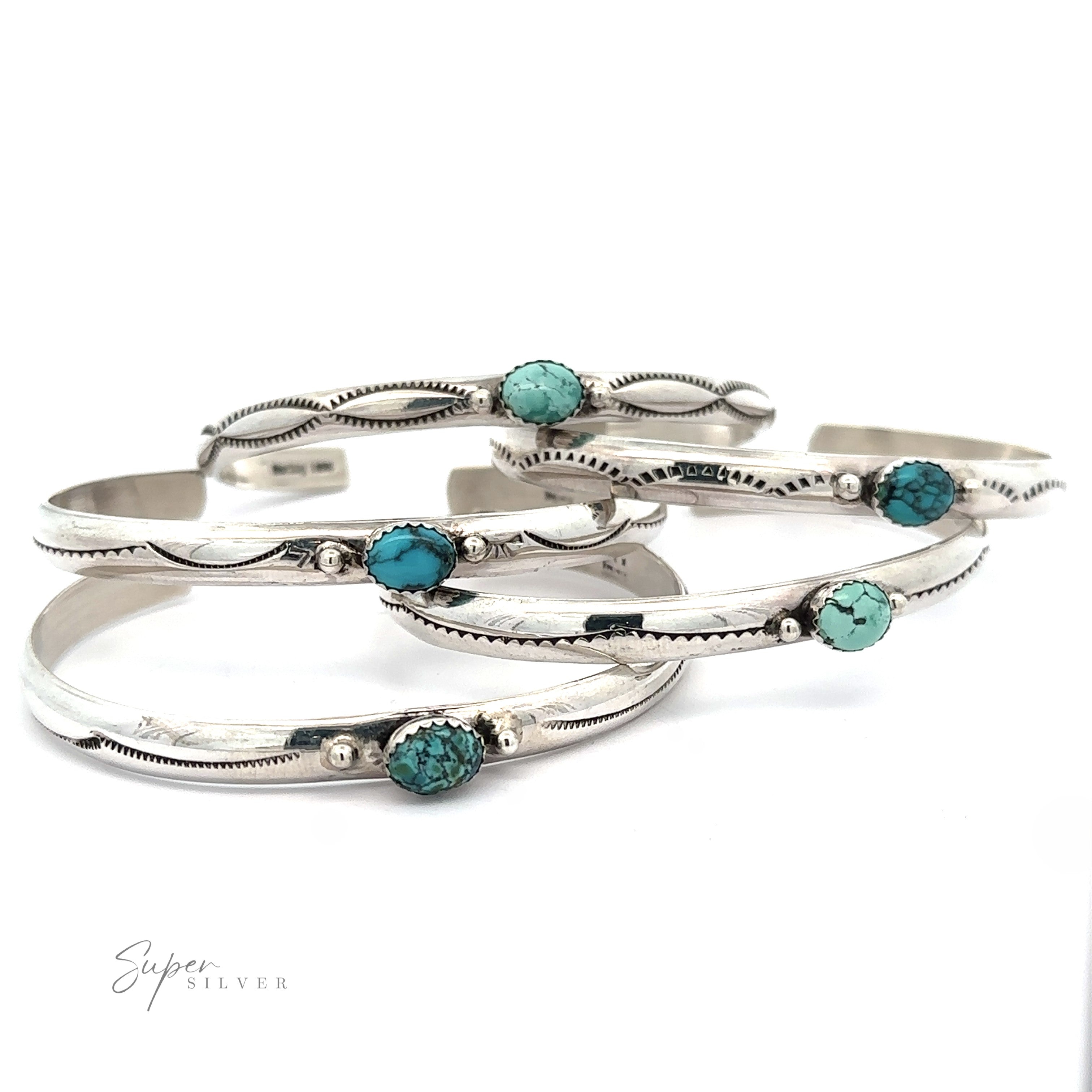 Four Striking Native American Turquoise Cuffs with Diamond Etching, each featuring Kingman Turquoise stones, are stacked together on a white surface. The cuffs have intricate detailing along the edges, reminiscent of a handcrafted Navajo cuff. The words "Super Silver" are in the bottom-left corner.