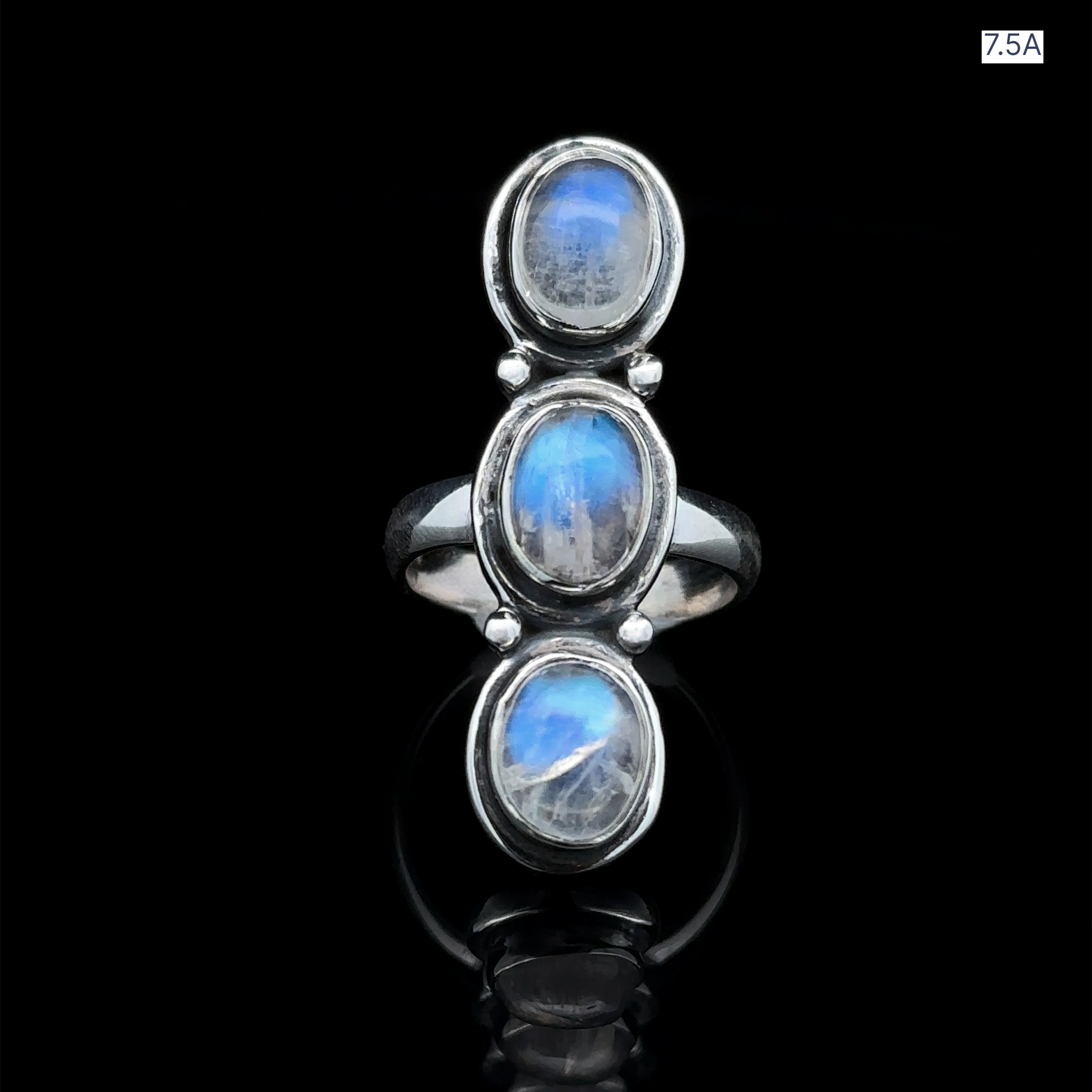 The Triple Moonstone Ring, crafted in sterling silver with three vertically arranged oval cabochons, radiates goddess energy against a black background.