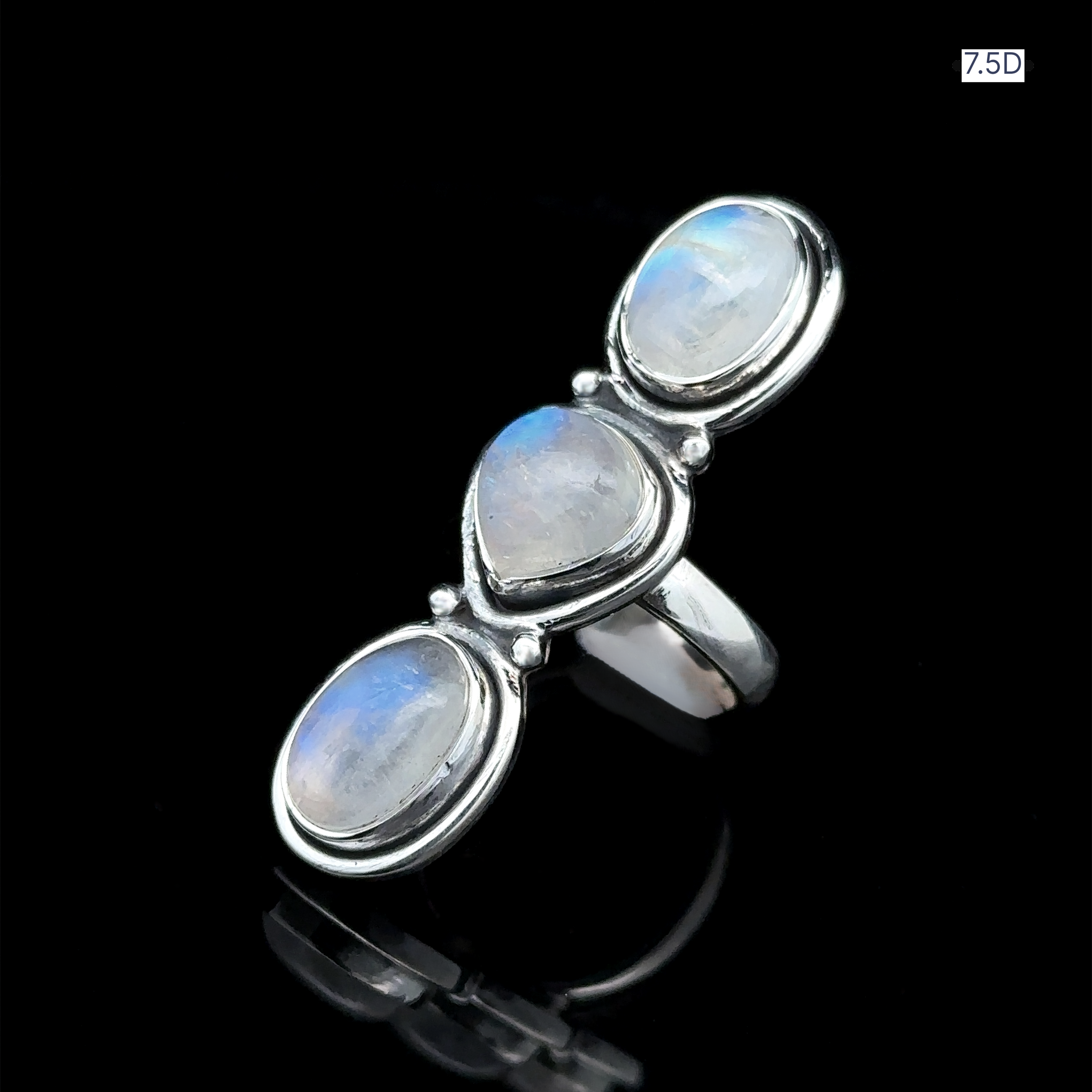 The Triple Moonstone Ring is crafted from sterling silver and showcases three oval moonstones set against a black background, exuding goddess energy.