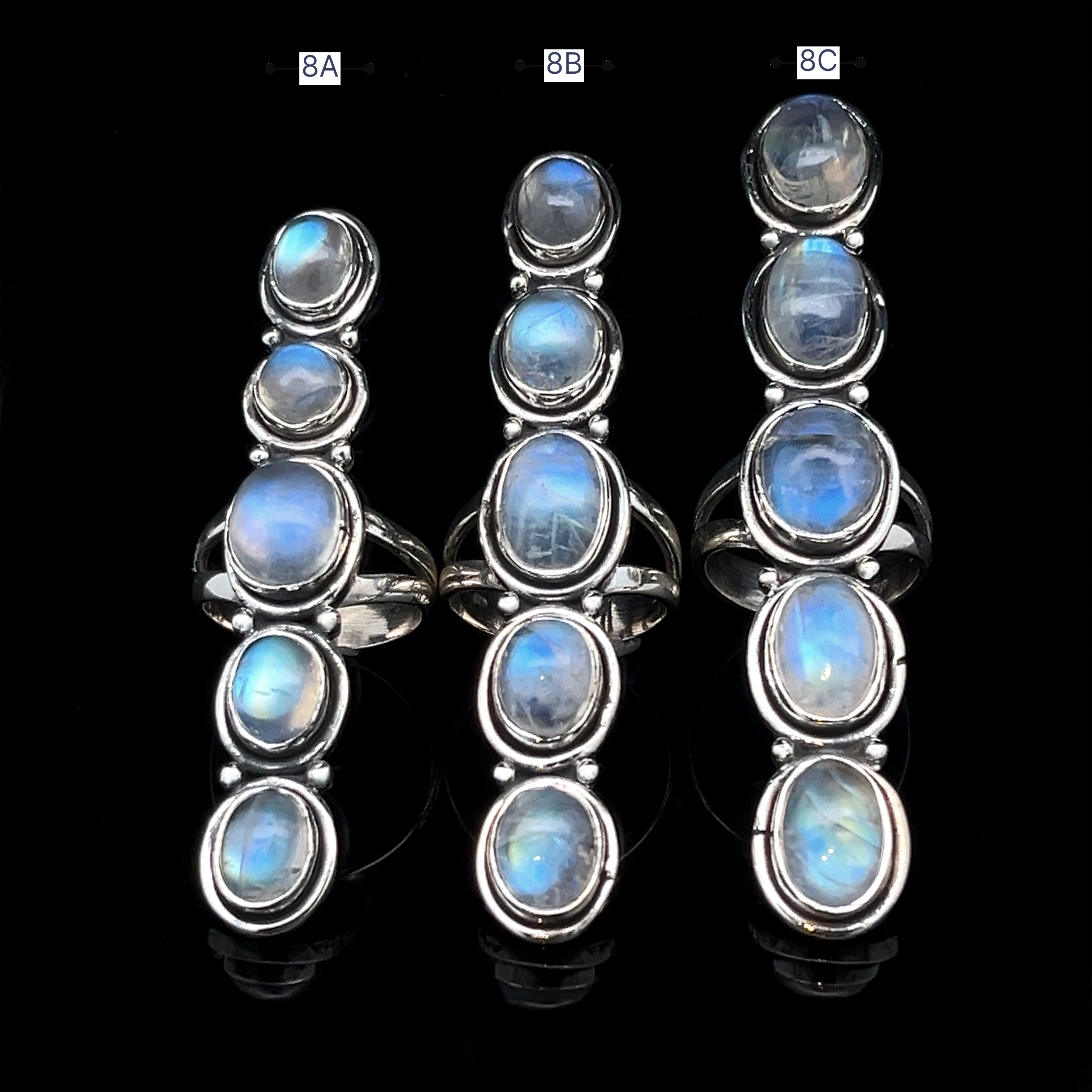 Three Moonstone Ladder Rings in sterling silver, each featuring five oval blue moonstone cabochons and labeled 8A, 8B, and 8C, are displayed vertically against a black background.