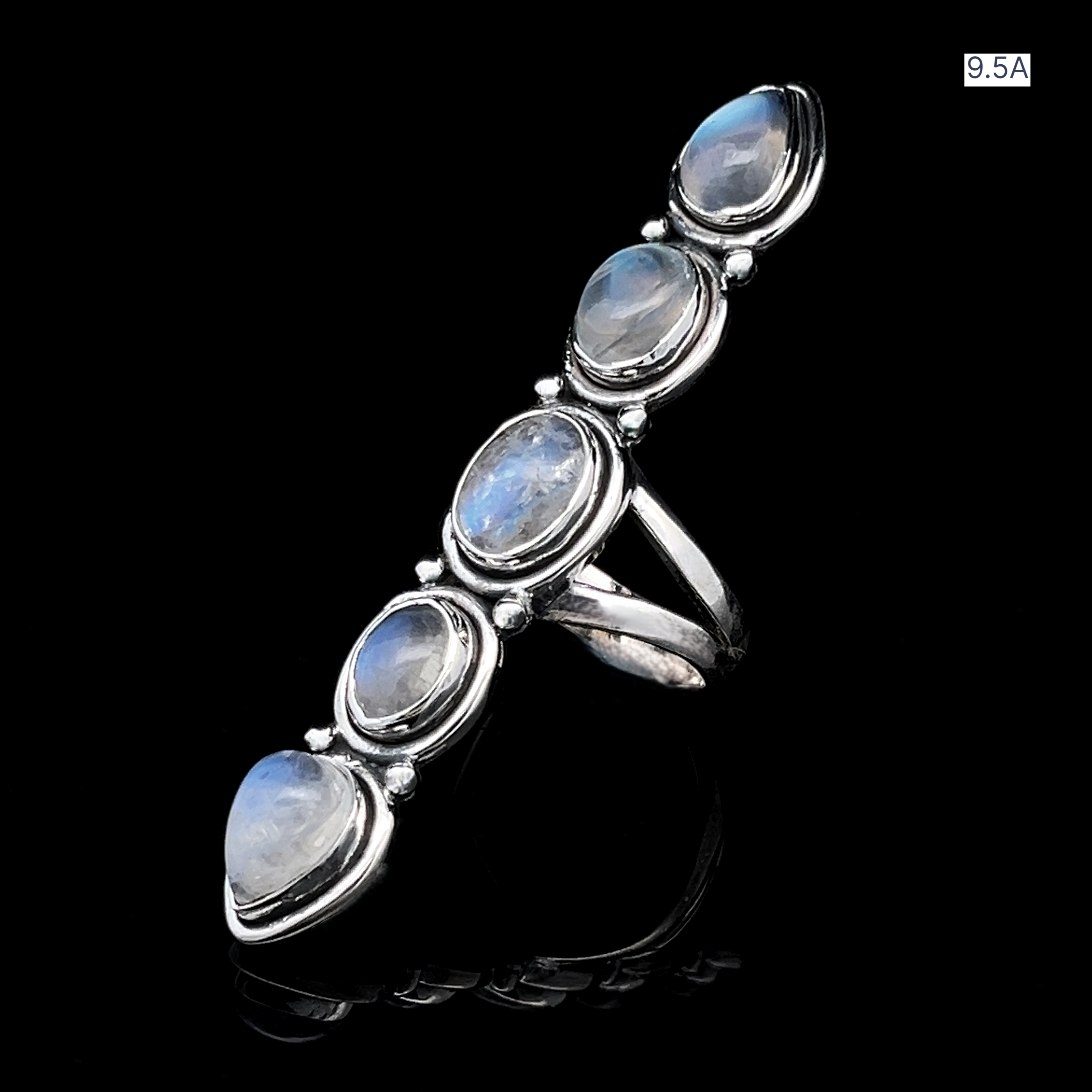 The Moonstone Ladder Ring features five oval and teardrop-shaped blue moonstones in a linear sterling silver setting, showcased on a reflective black surface.