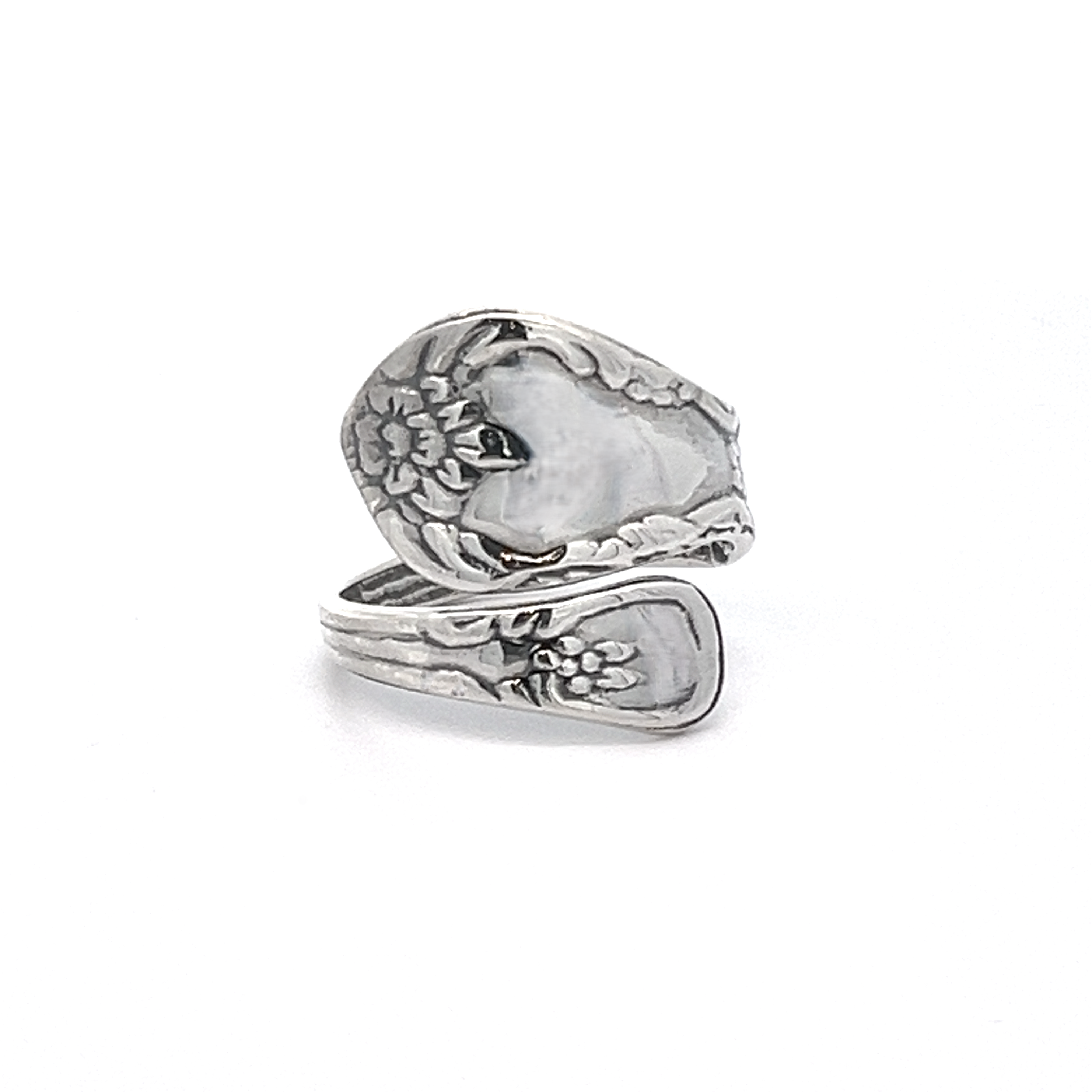 A Timeless Spoon Ring showcasing a floral pattern, with a coiled design where the handle forms the band, and finished with a polished touch.
