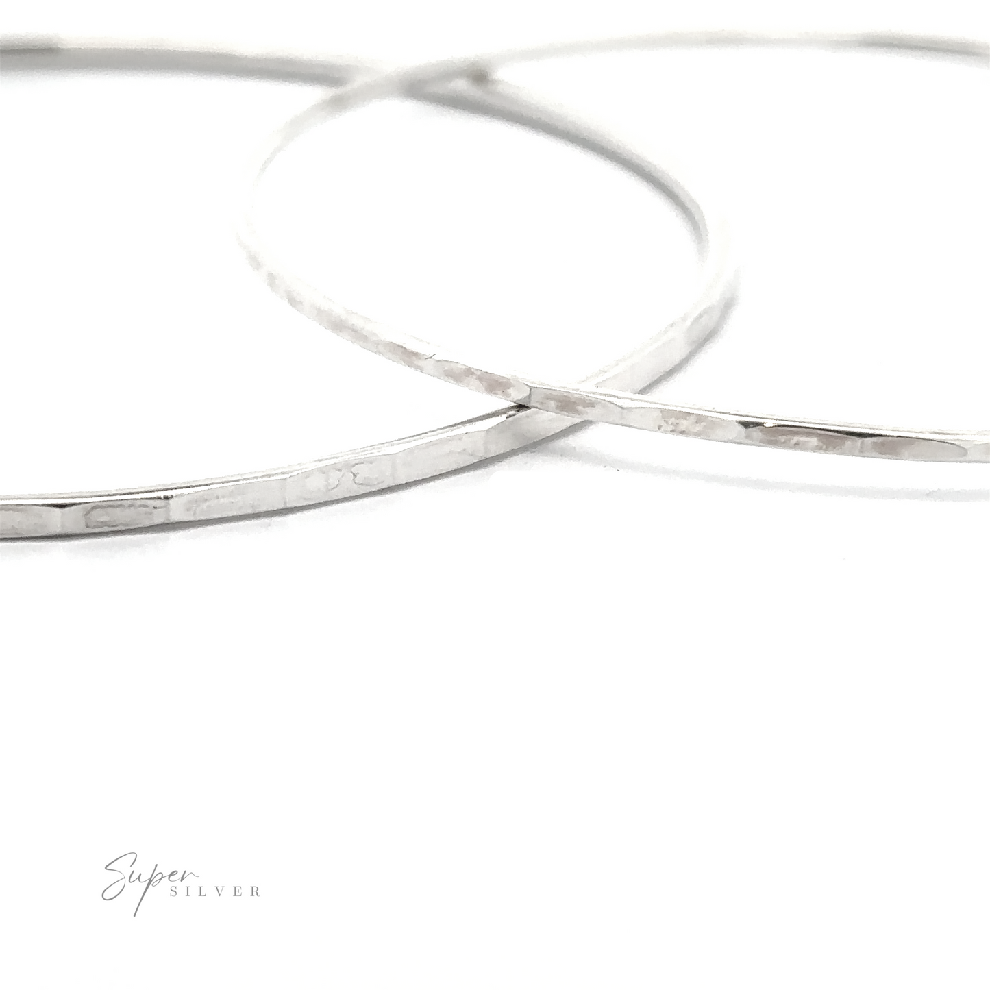 
                  
                    Two Faceted Silver Bangle Bracelets on a white surface.
                  
                