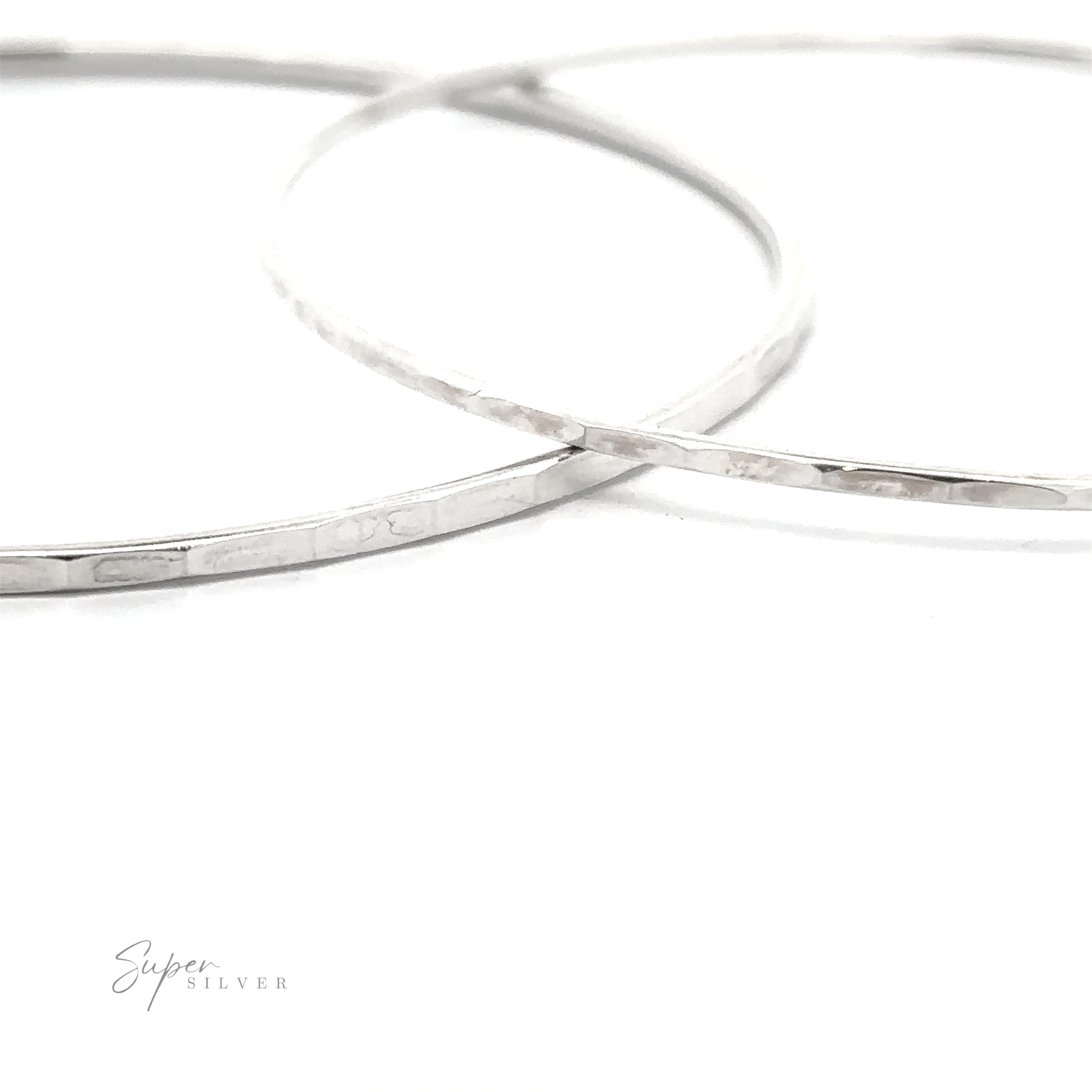 Two Faceted Silver Bangle Bracelets on a white surface.