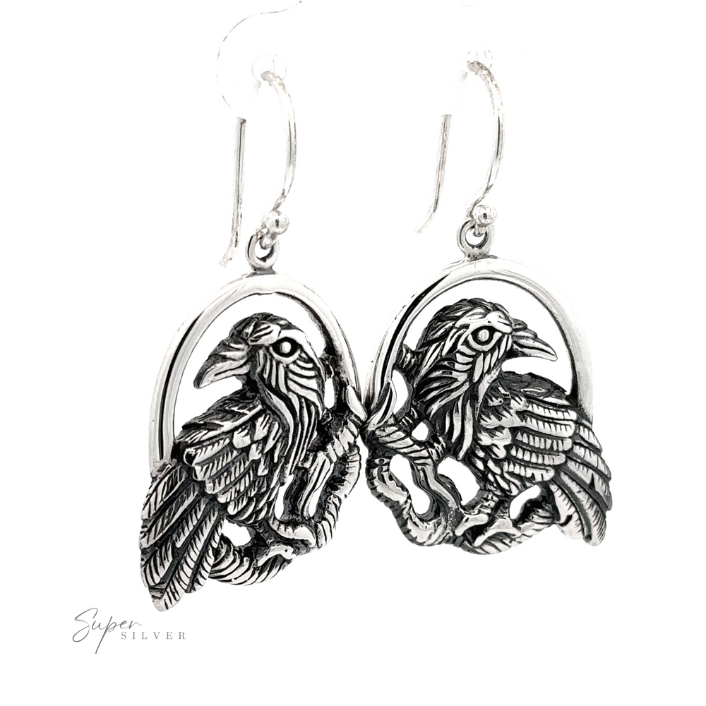 A pair of Detailed Raven Earrings, each featuring an intricate eagle design, on a white background with a 