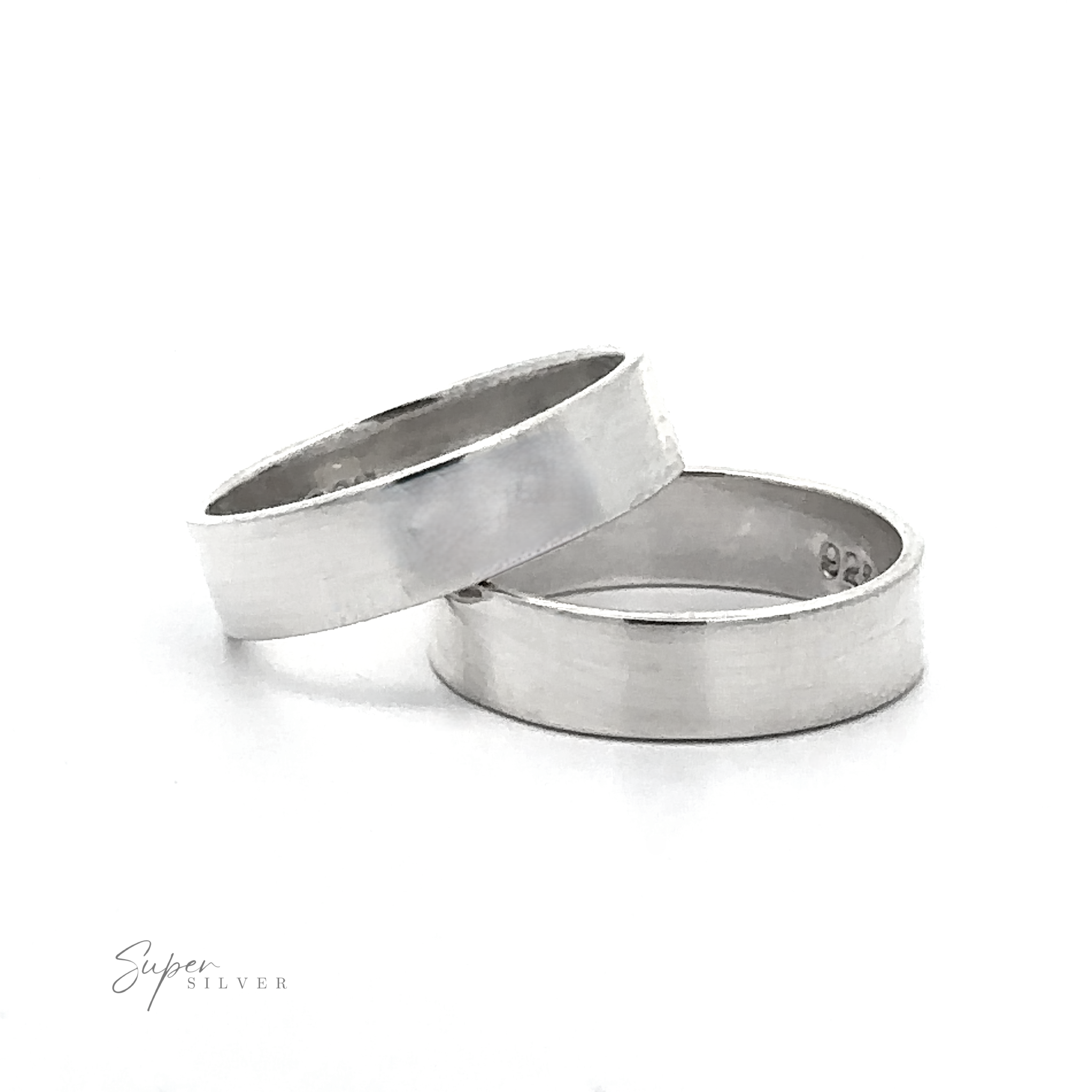 Two Minimal Bold Flat Band sterling silver rings are stacked together on a white background, with a small engraving visible on the inner side of one band.