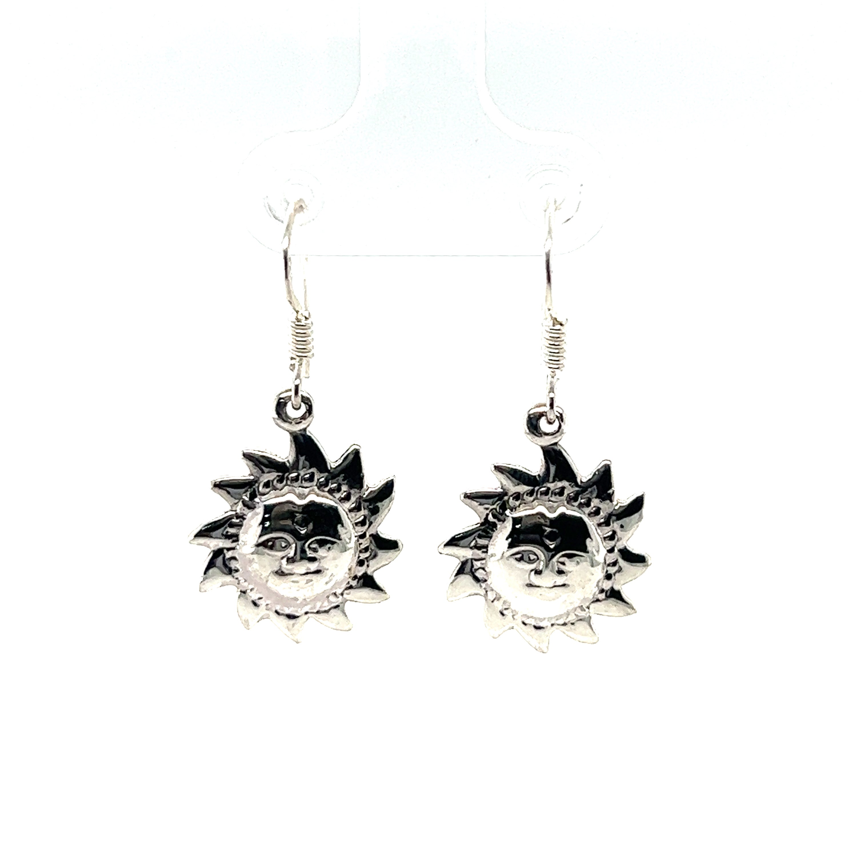 A pair of small Super Silver sun with face earrings on a white background.