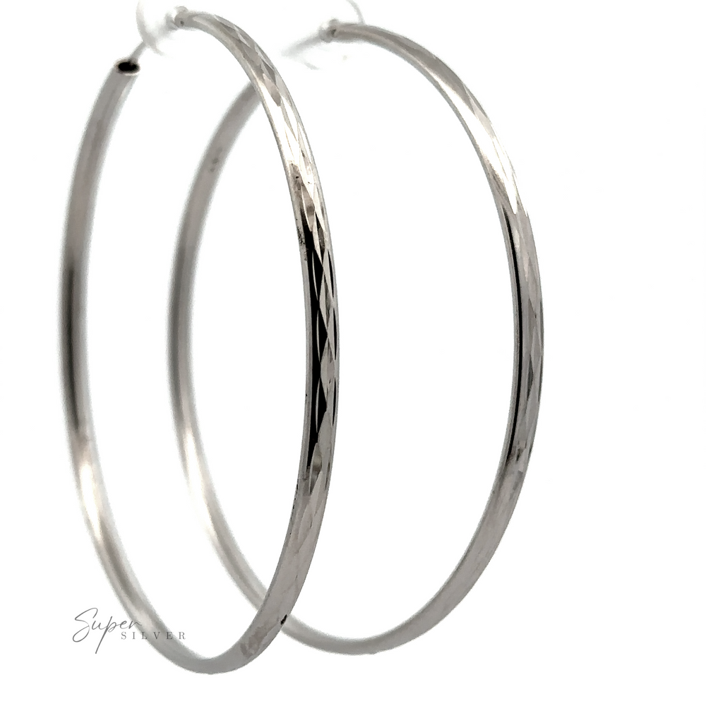 
                  
                    A close-up image of two Flashy 60mm Diamond Faceted Hoops against a white background, with a subtle reflection and a signature in the corner.
                  
                