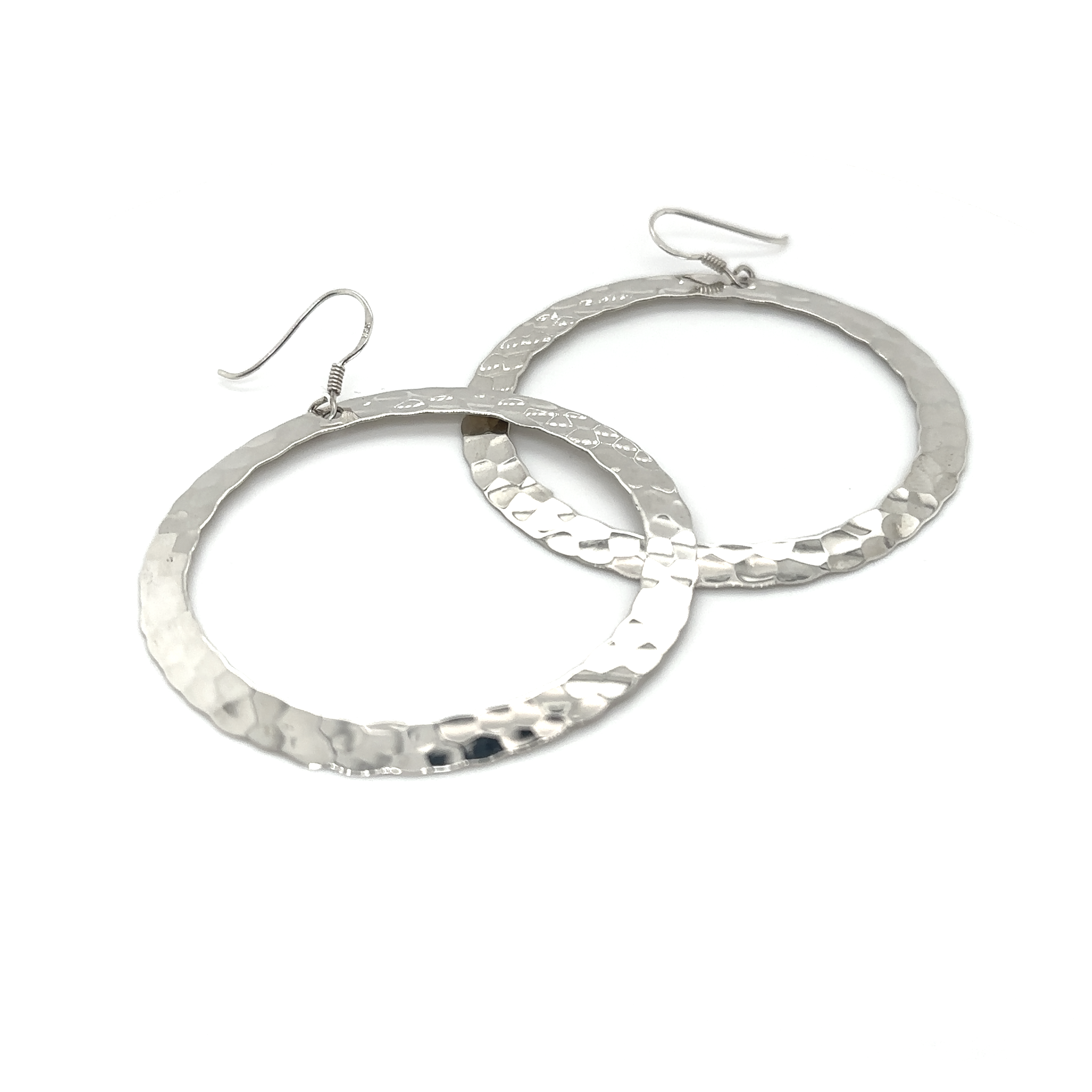 The Hammered Open Circle Earrings feature large, round, hammered silver hoops with hook closures—ideal for anyone who loves bold statement jewelry. Displayed on a white background.