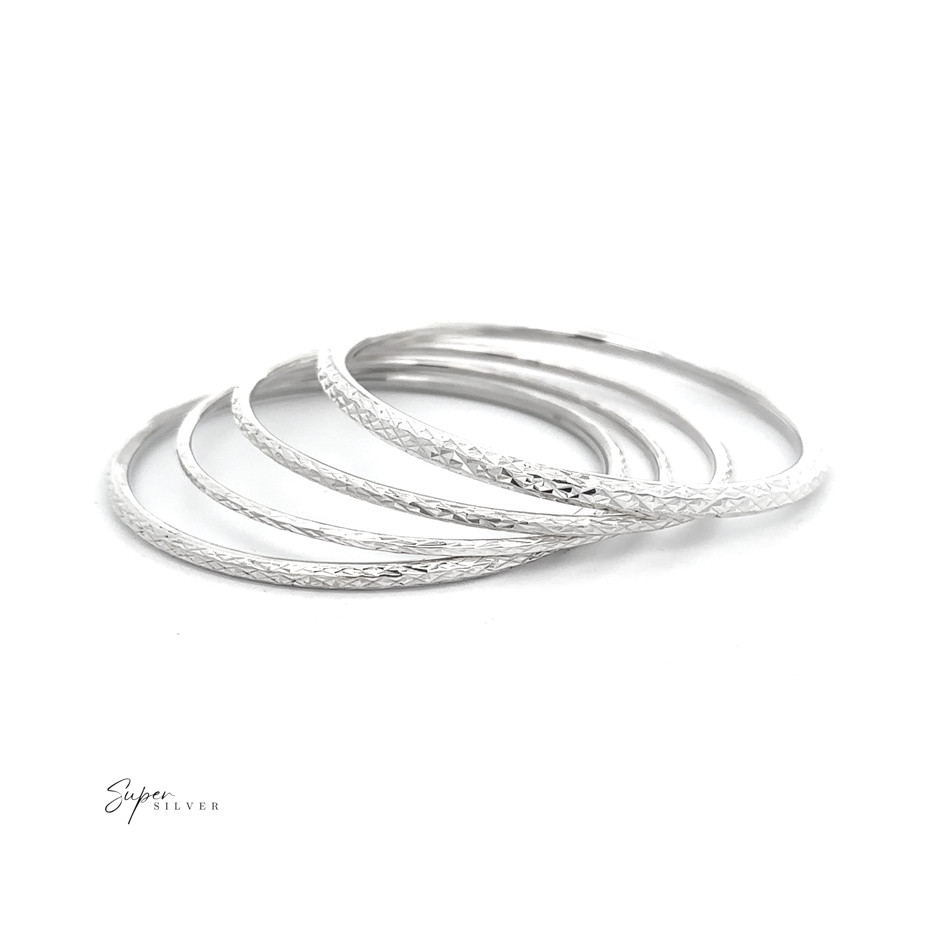 A set of five thin, faceted bangles from The Spark Stack Bangles overlaps on a white background with 'Super Silver' in the lower left corner—perfect for adding an elegant jewelry touch to any outfit.