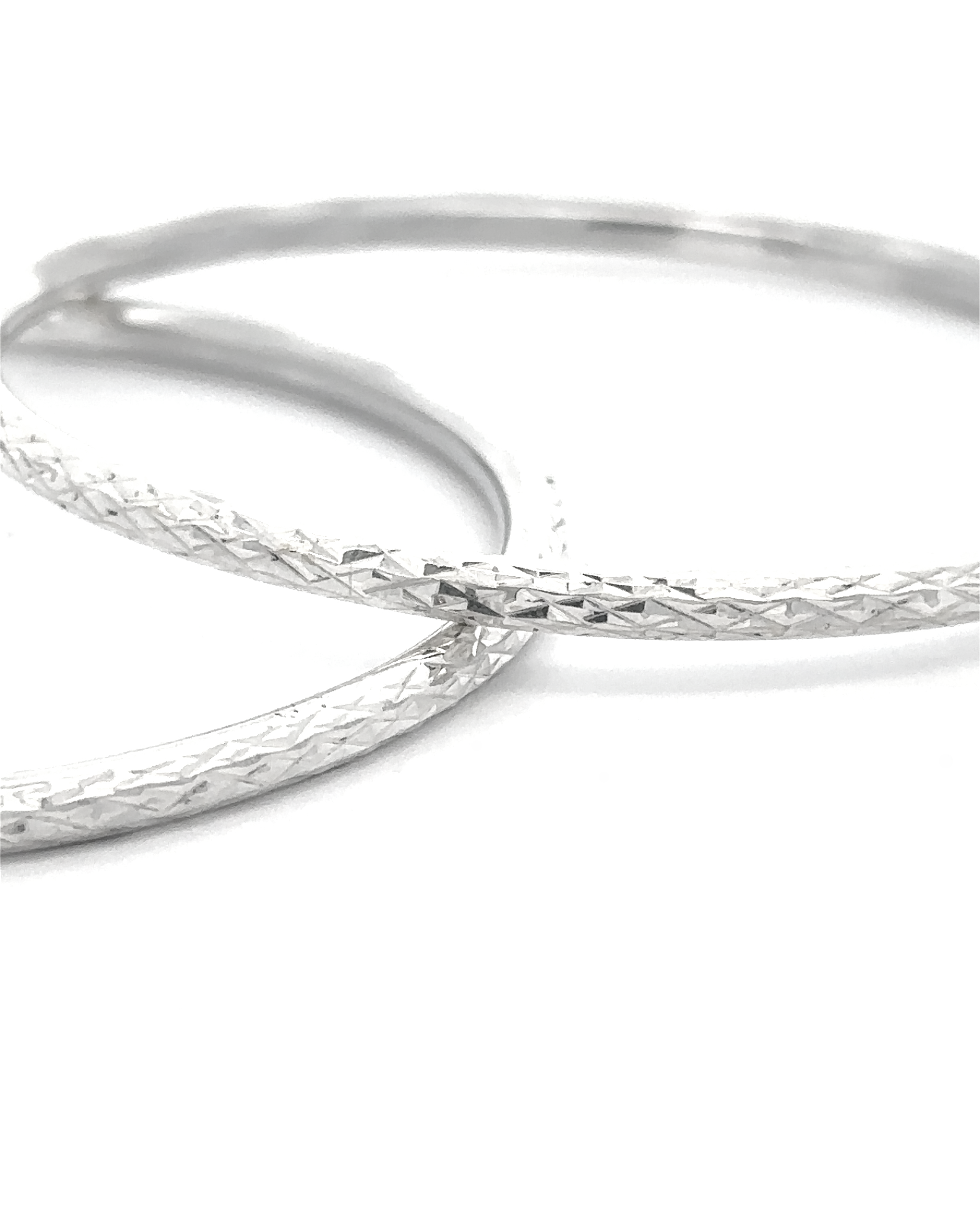 The Spark Stack Bangles—two slender sterling silver bangles with a textured crisscross design—overlap gracefully on a white background, offering an elegant touch of sophistication to any style.