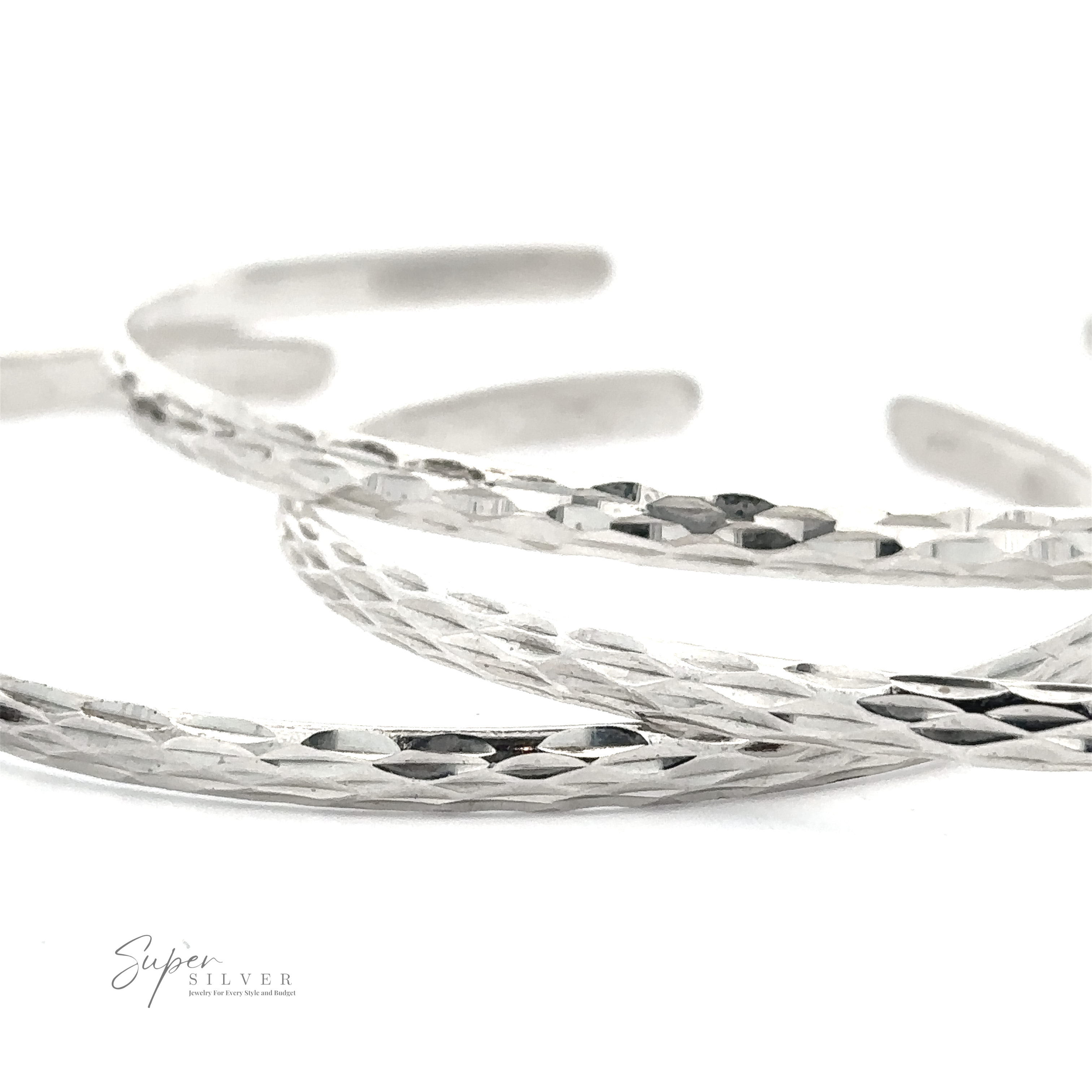 Close-up image of several Glittering Diamond Cut Cuff Bracelets overlapping each other, with "Super Silver" logo in the bottom left corner.