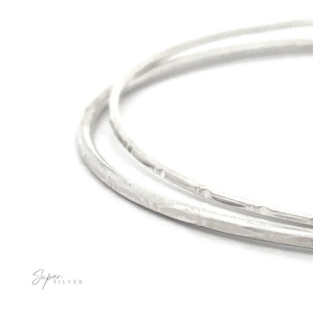 
                  
                    Close-up of two thin, faceted Sparkling Faceted Bangle Bracelet overlapped against a white background with "Super Silver" text in the bottom left corner.
                  
                