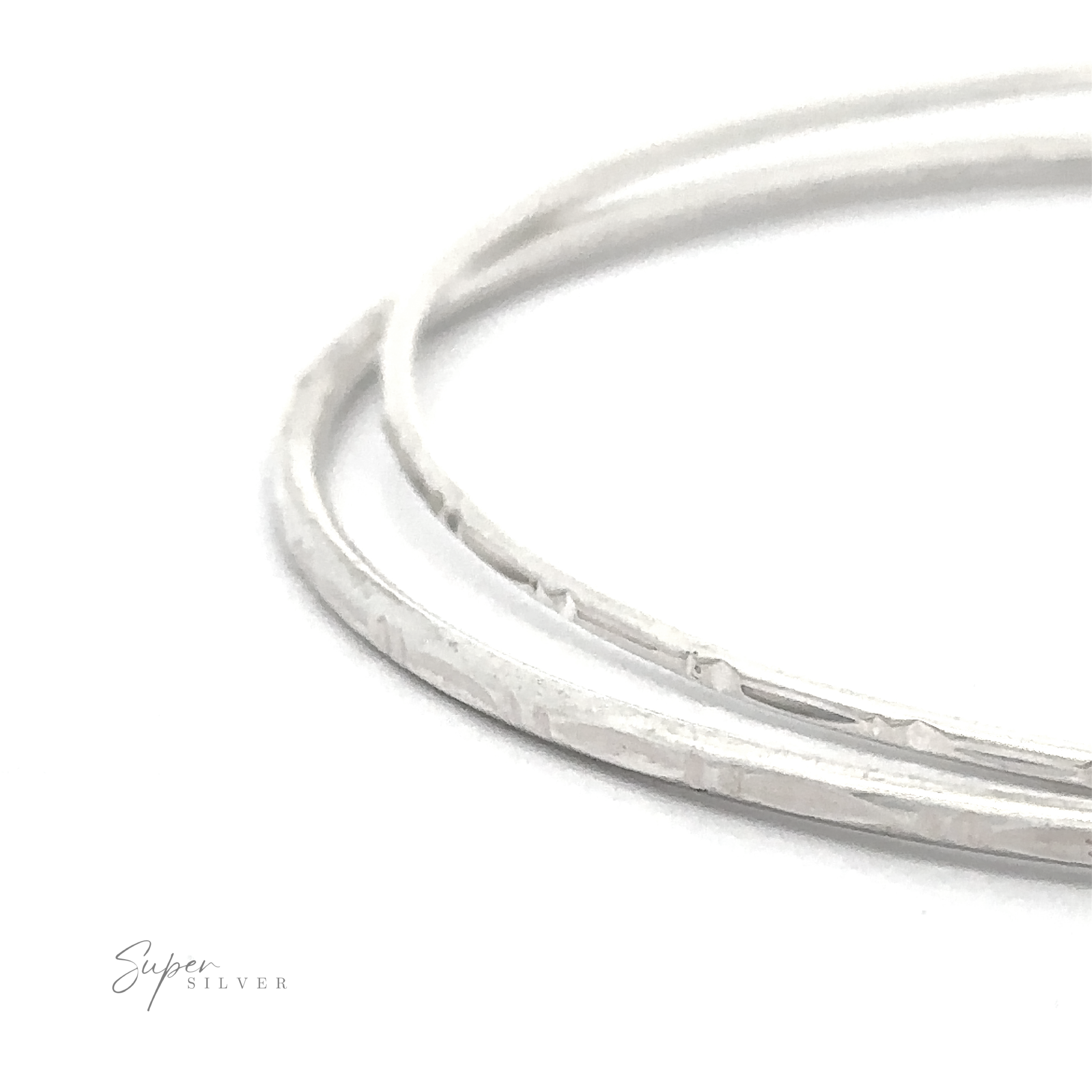 Close-up of two thin, faceted Sparkling Faceted Bangle Bracelet overlapped against a white background with "Super Silver" text in the bottom left corner.