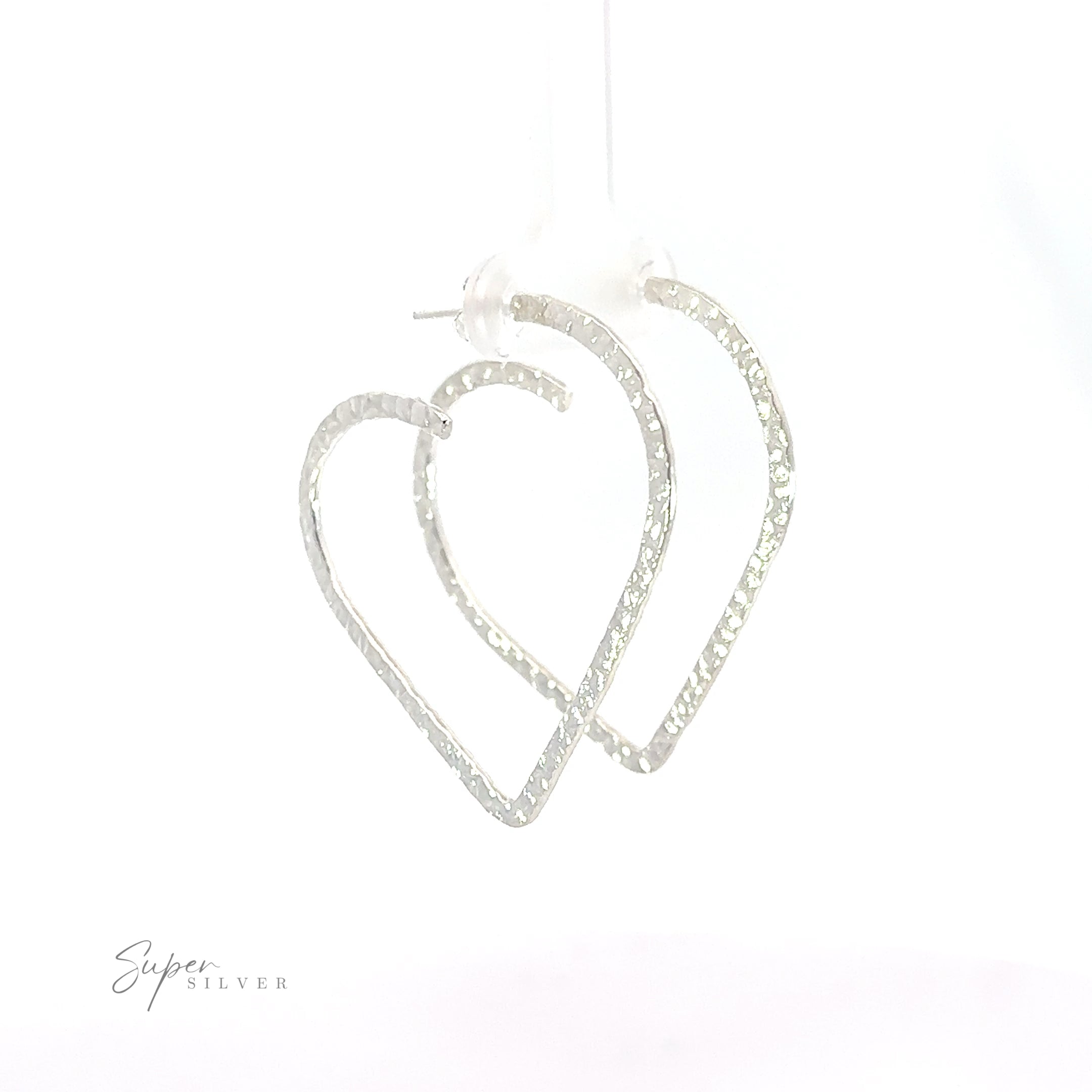 Two silver Textured Heart Hoop Earrings hanging on a white background.