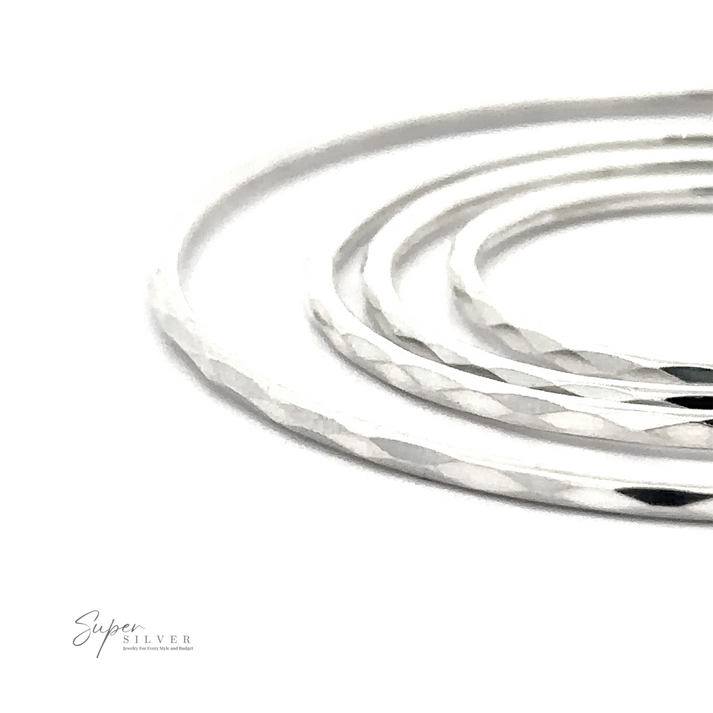 Close-up of 1.5mm Faceted Silver Infinity Hoops with a rhodium finish, displayed against a white background with a logo reading 