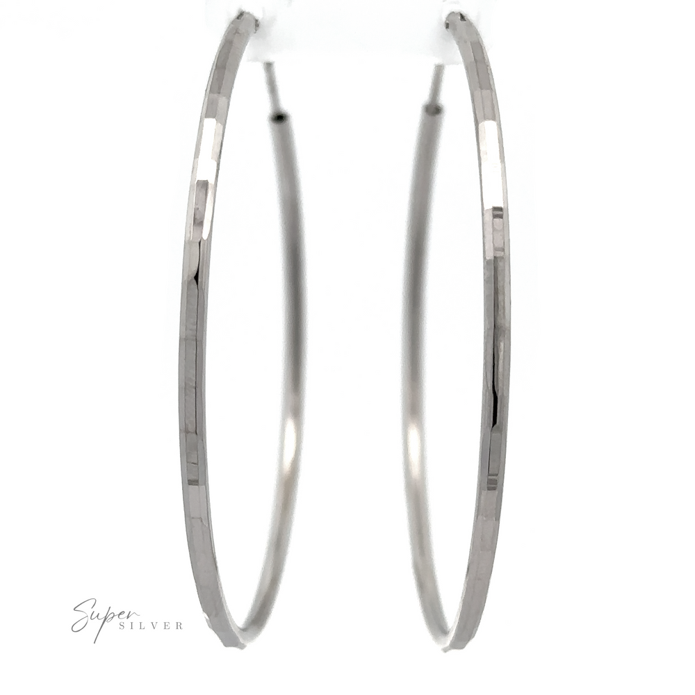 
                  
                    2mm Diamond Cut Hoop Earrings with a thin, slightly angular design, crafted from .925 sterling silver, presented on a white background with a reflective surface below and a "super silver" signature.
                  
                