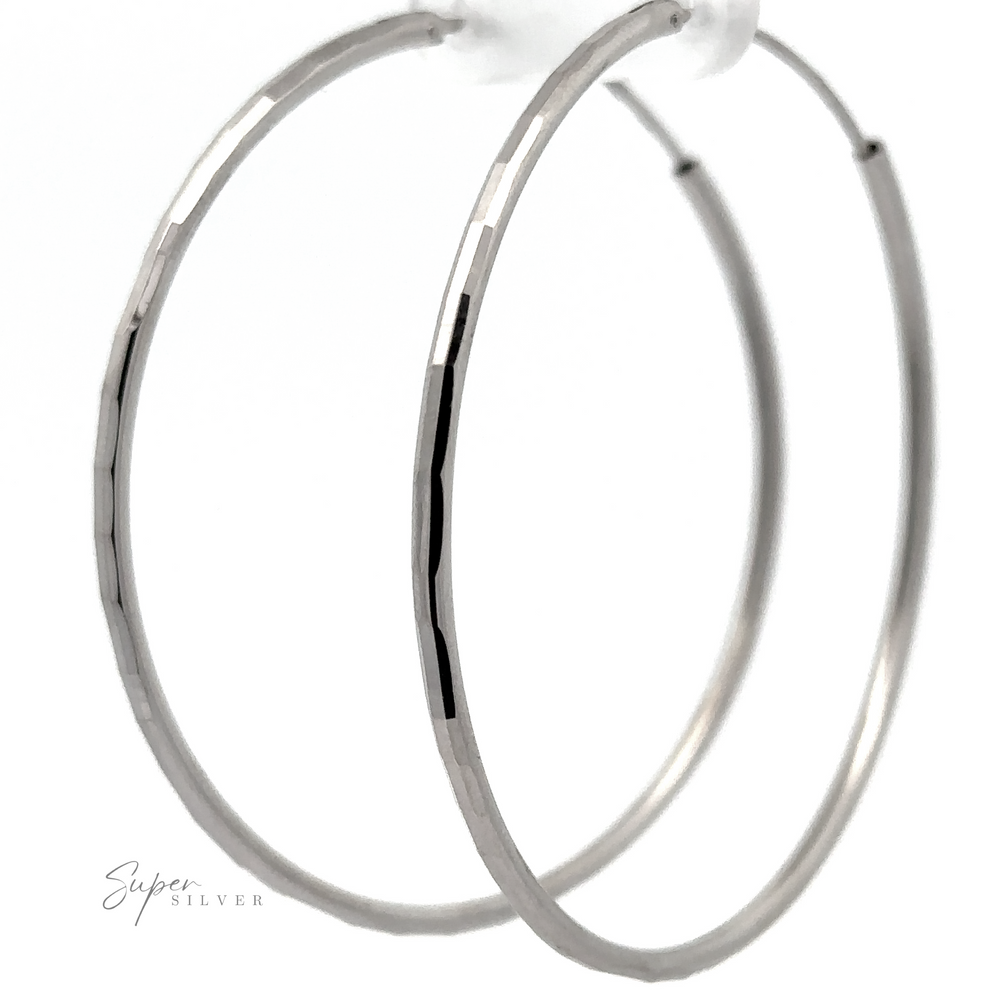 
                  
                    A close-up of two 2mm Diamond Cut Hoop Earrings with a rhodium finish, displayed against a white background.
                  
                