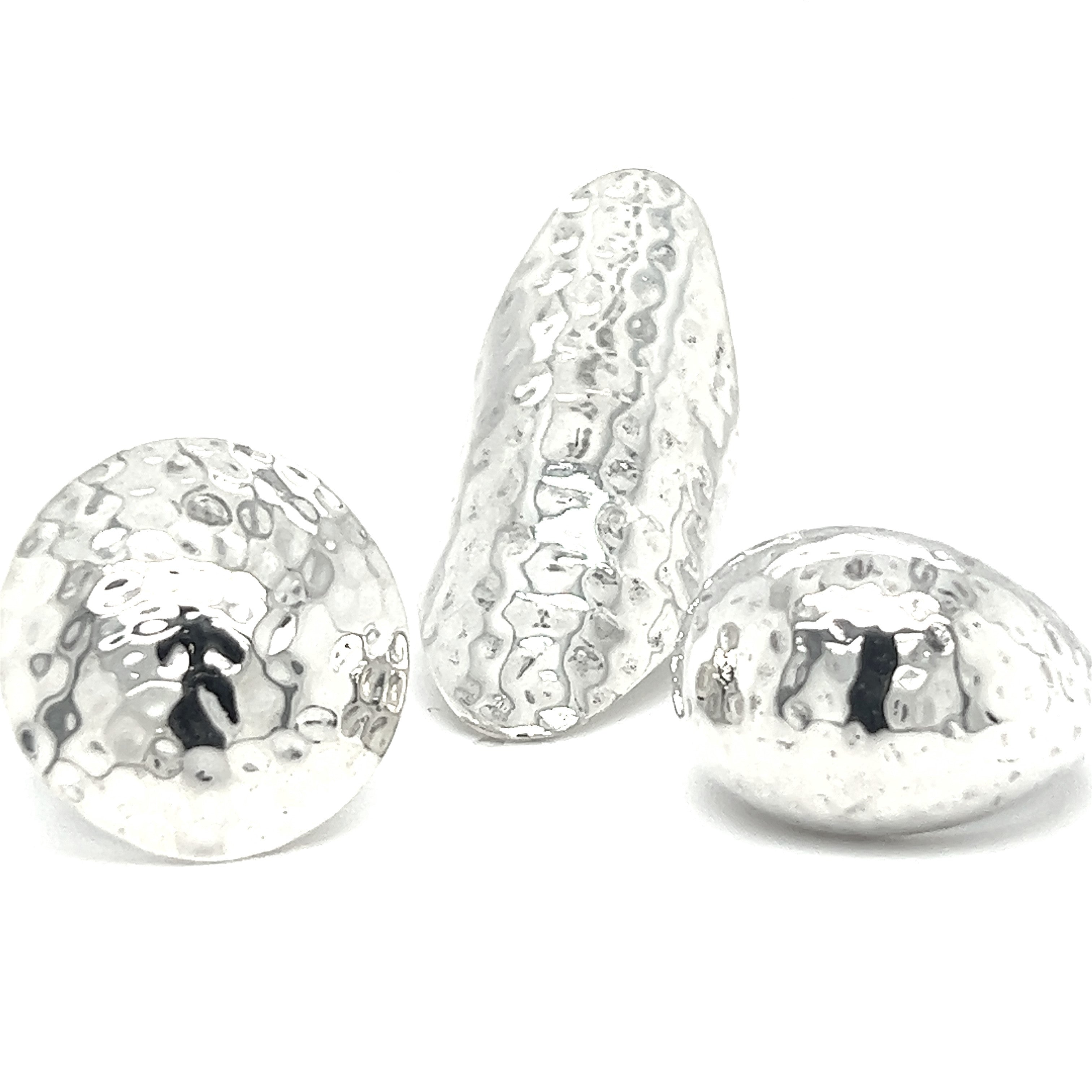 Three silver hammered Statement Hammered Rings on a white surface, part of the Silver Hammered Ring collection.