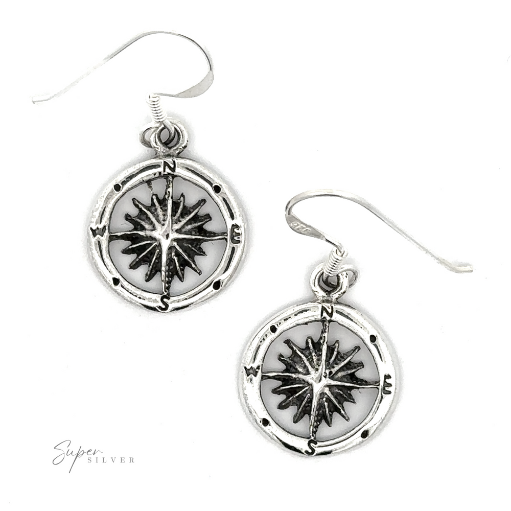 Pair of Compass Dangling Earrings with circular pendants featuring a blackened relief of a compass rose design, displayed on a white background.